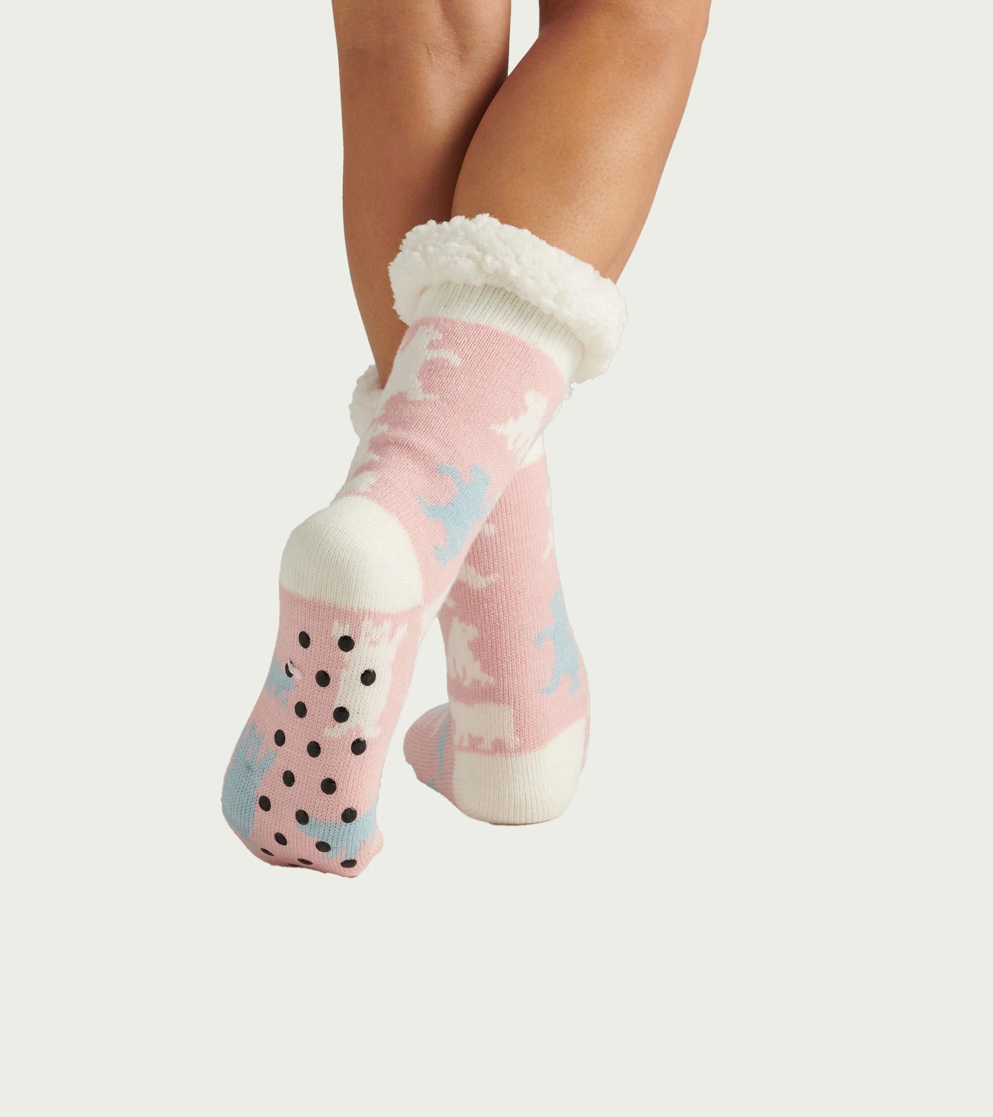 Pink sherpa-lined cabin socks with polar bear pattern and black grippy dots on the sole, worn on feet