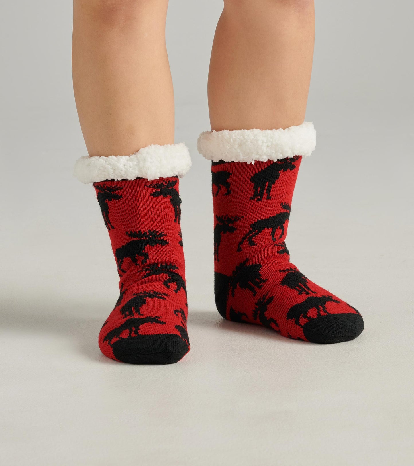 Red cabin socks featuring black moose patterns and a soft white sherpa lining at the cuff. One size fits most.