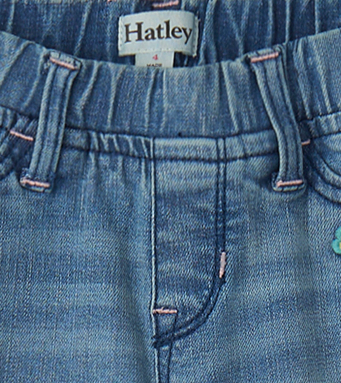 Light blue stretch jeans with a soft waistband and decorative patches, featuring pink stitching and front pockets.