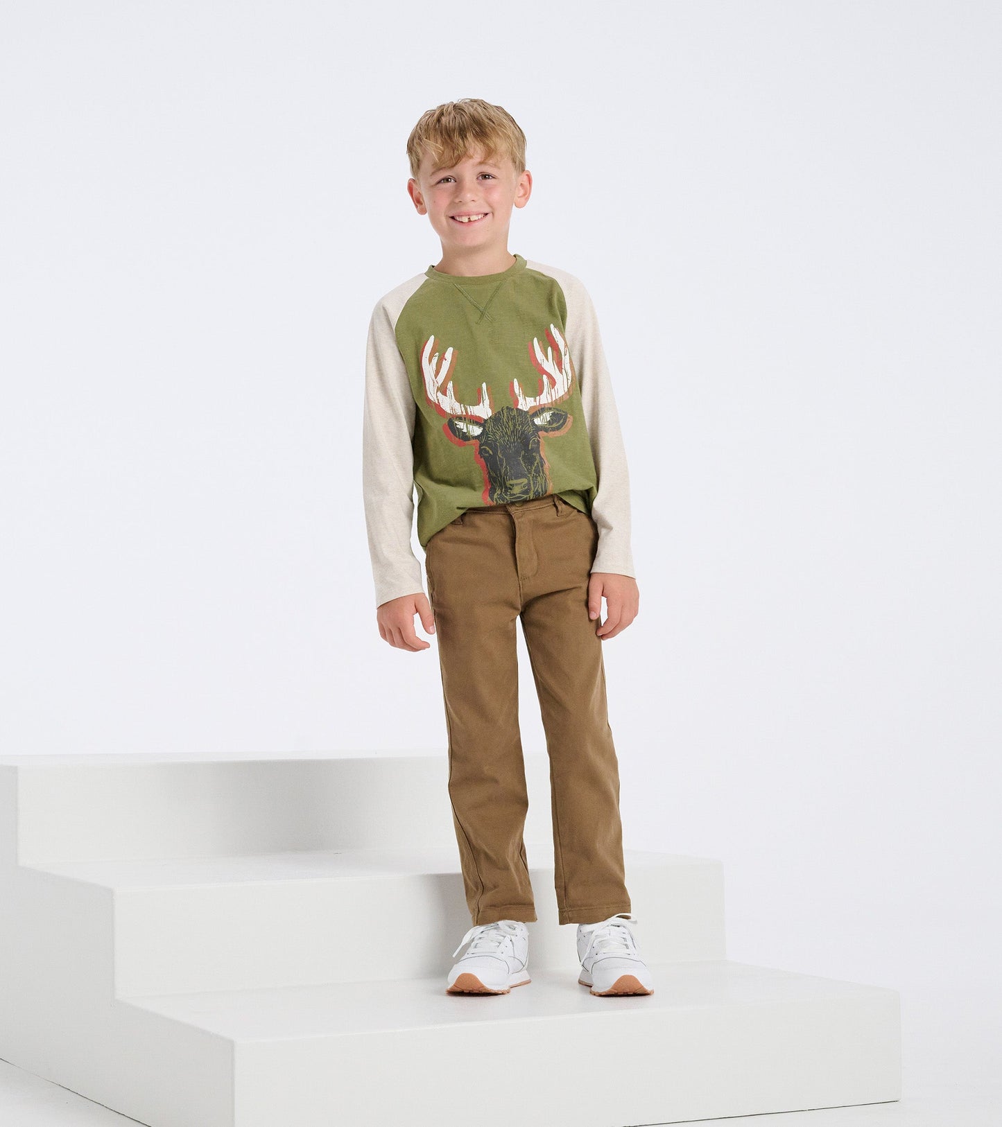 Khaki twill pants for boys, featuring a straight fit and lightweight fabric, paired with a green graphic long-sleeve shirt.
