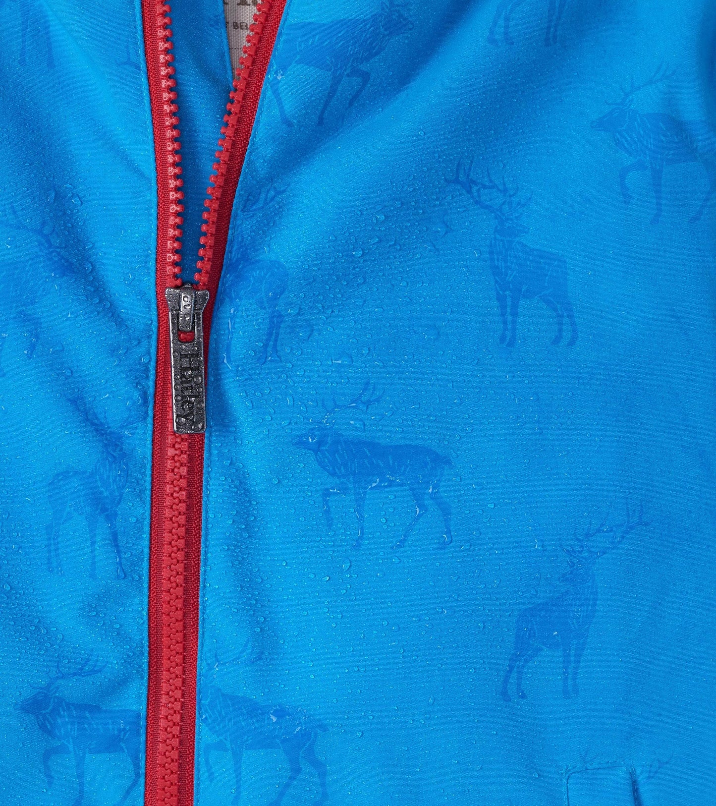 Lightweight blue rain jacket with red zipper, featuring a subtle elk pattern and water droplets on the fabric.