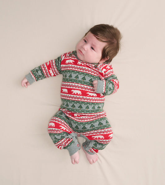 Red and green Fair Isle sweater romper with polar bear and tree patterns, designed for infants, shown on a light background.