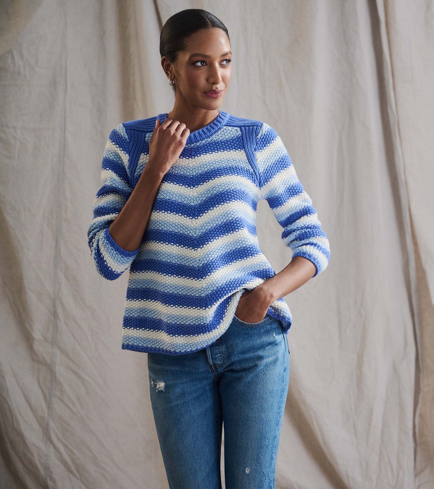 Navy blue chevron-patterned sweater with long sleeves, featuring a round neckline and relaxed fit, paired with jeans.