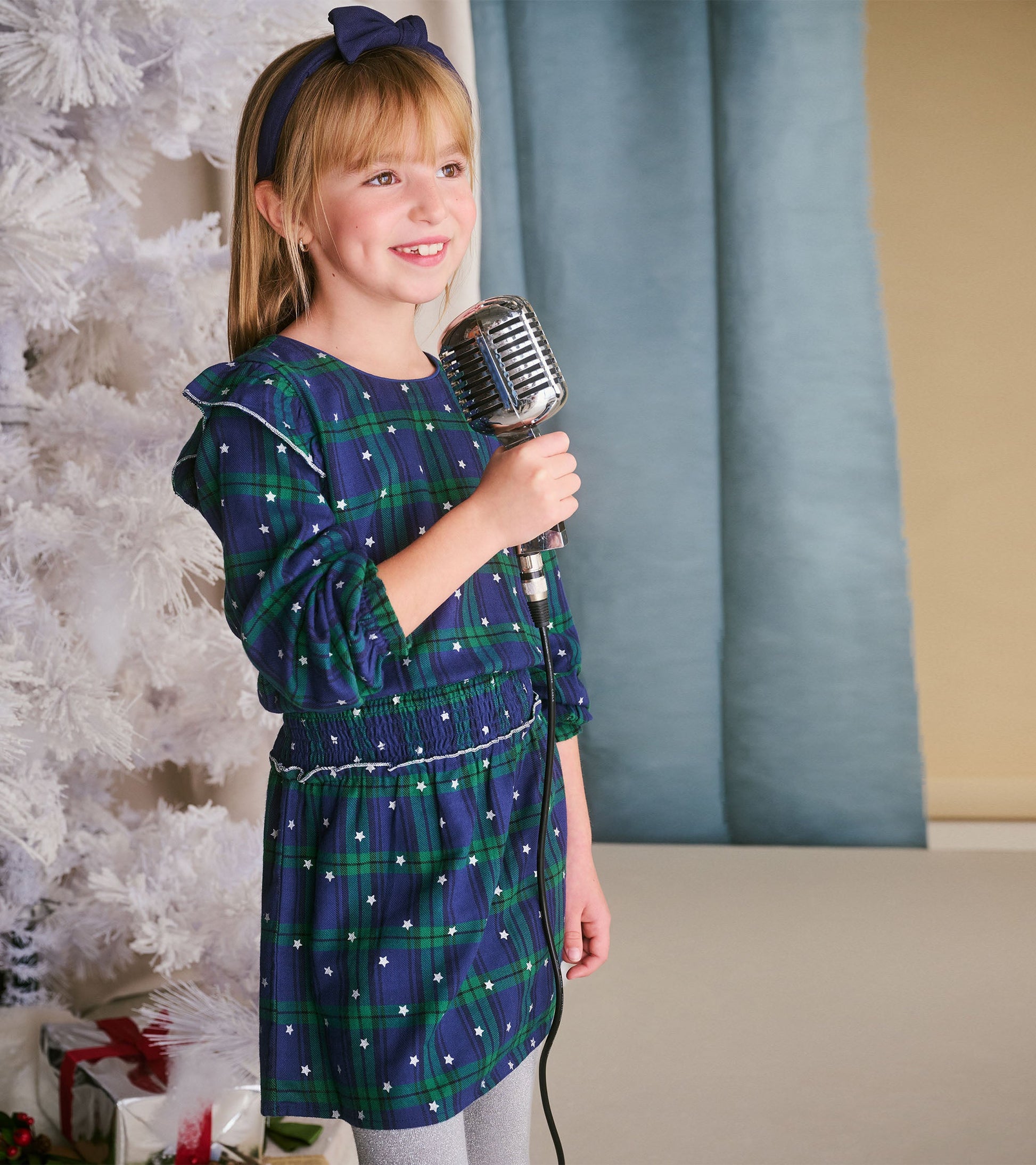 Girls' blackwatch plaid dress with smocked waist, long sleeves, and star accents, perfect for casual or festive occasions.