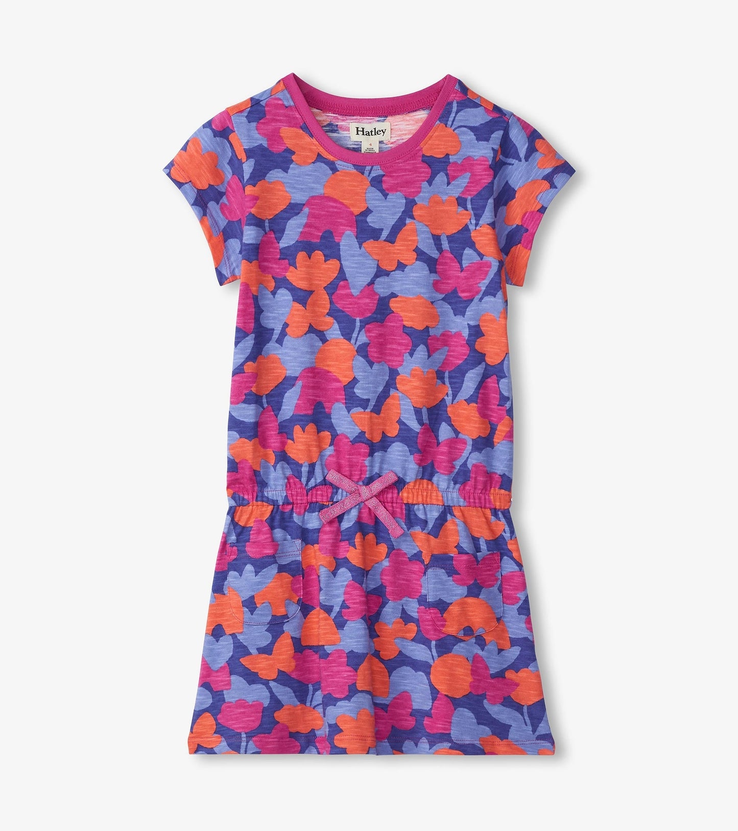 Colorful camo-patterned drop waist t-shirt dress in purple, pink, and orange with short sleeves and a bow detail.