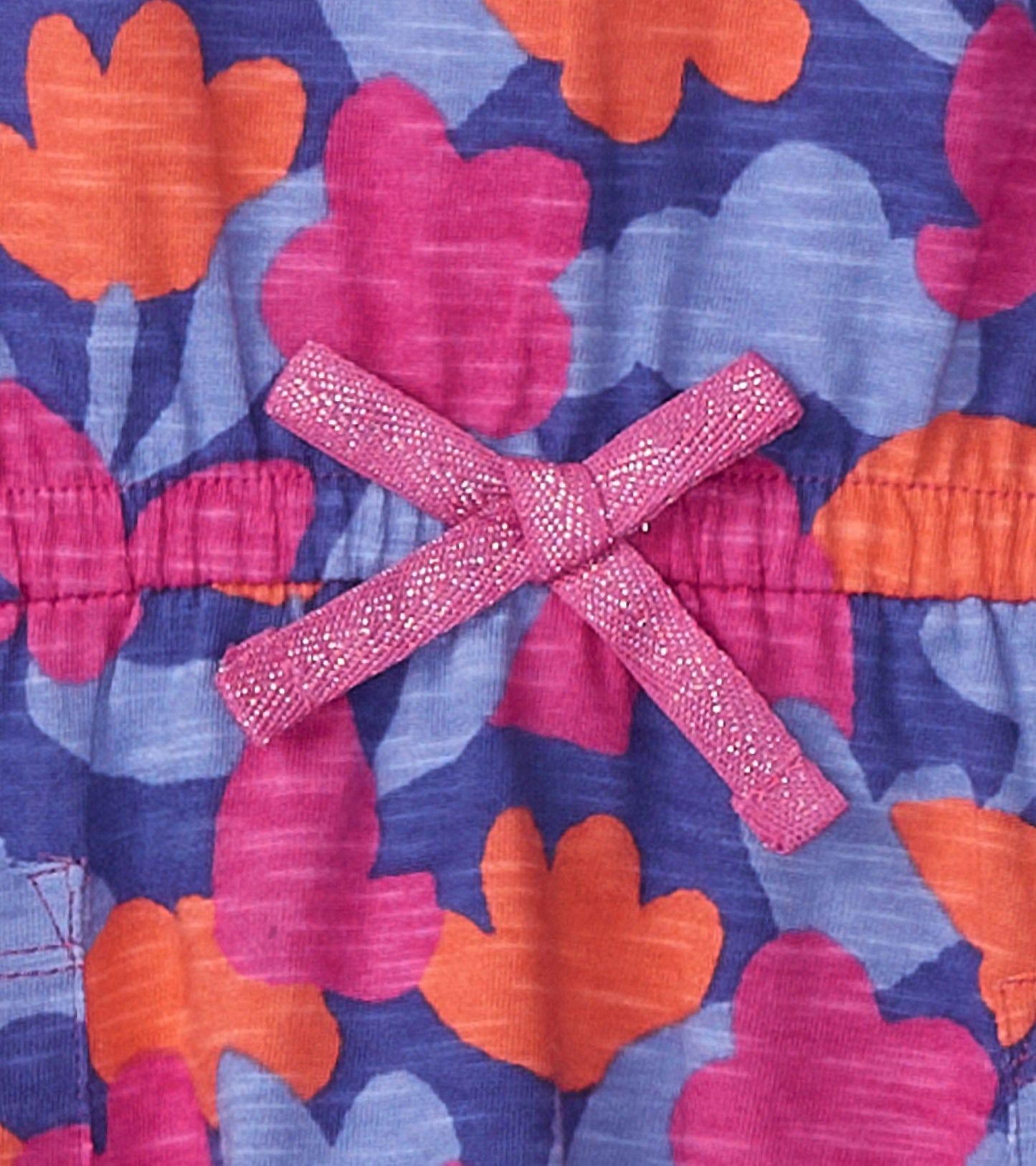 Colorful floral pattern with pink, orange, and blue hues; features a sparkly pink bow at the waist.