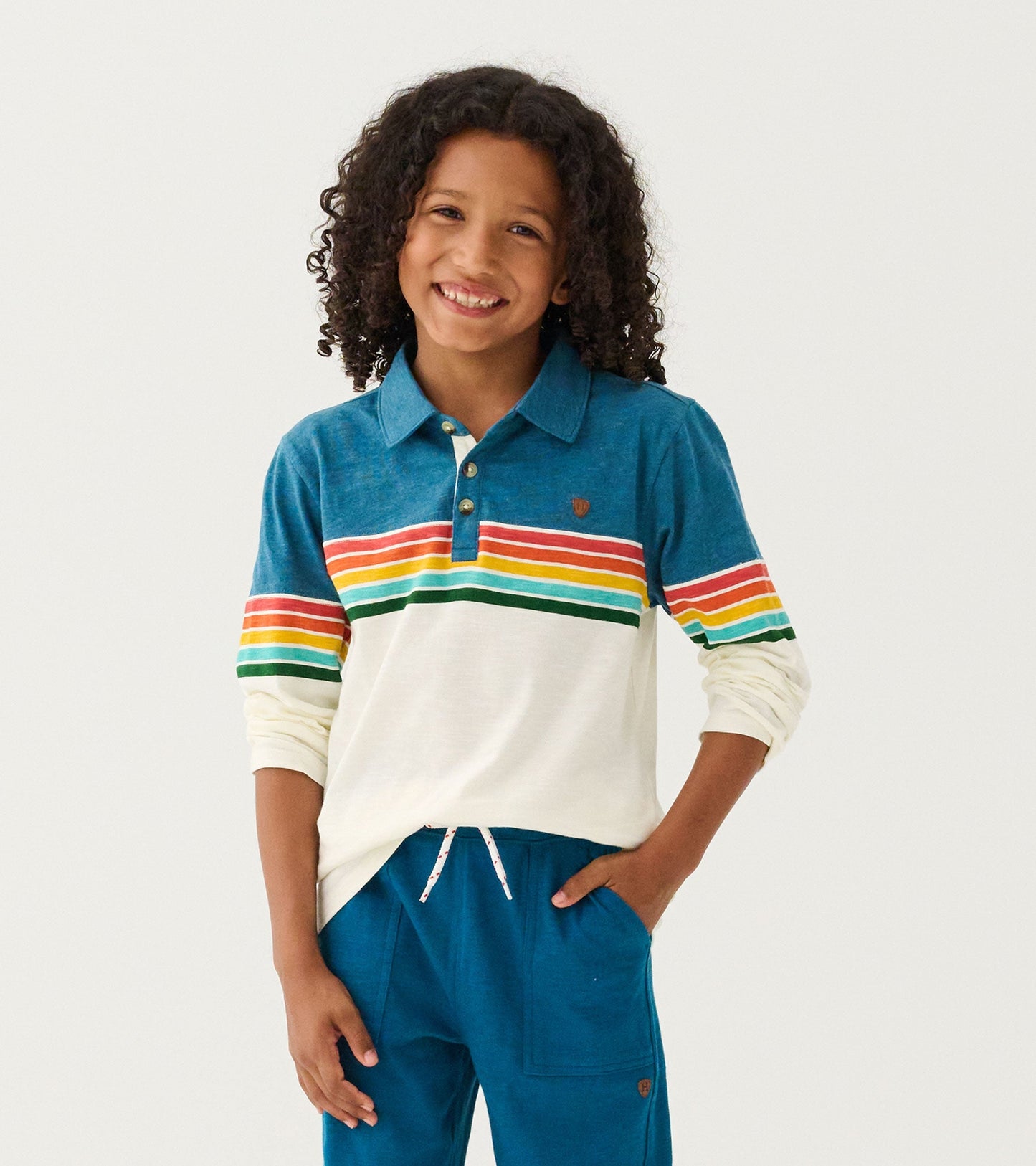 Long sleeve polo featuring a blue top with colorful retro stripes and a cream bottom, perfect for casual wear.