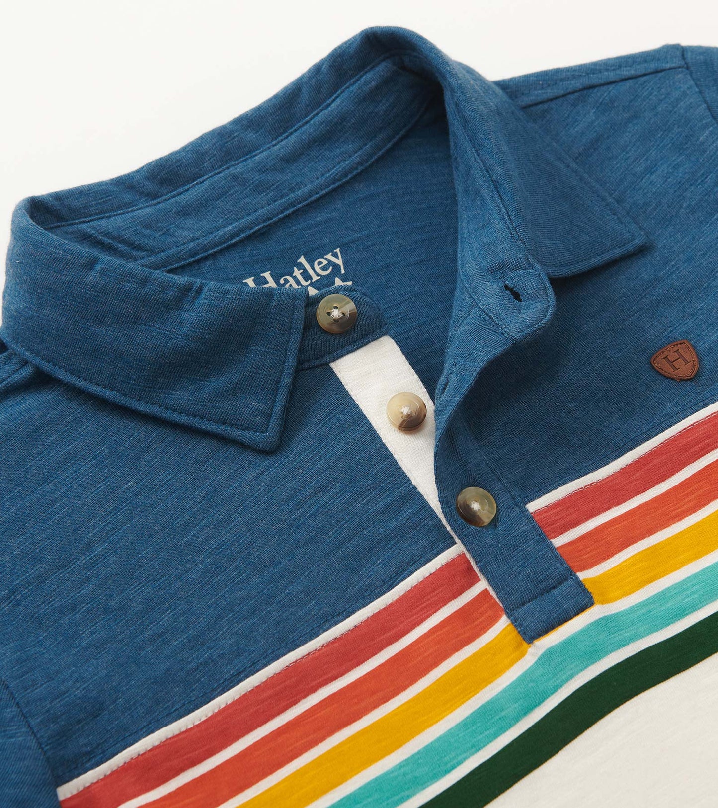 Blue long sleeve polo with retro stripes in red, yellow, green, and white; features a buttoned collar and chest logo.