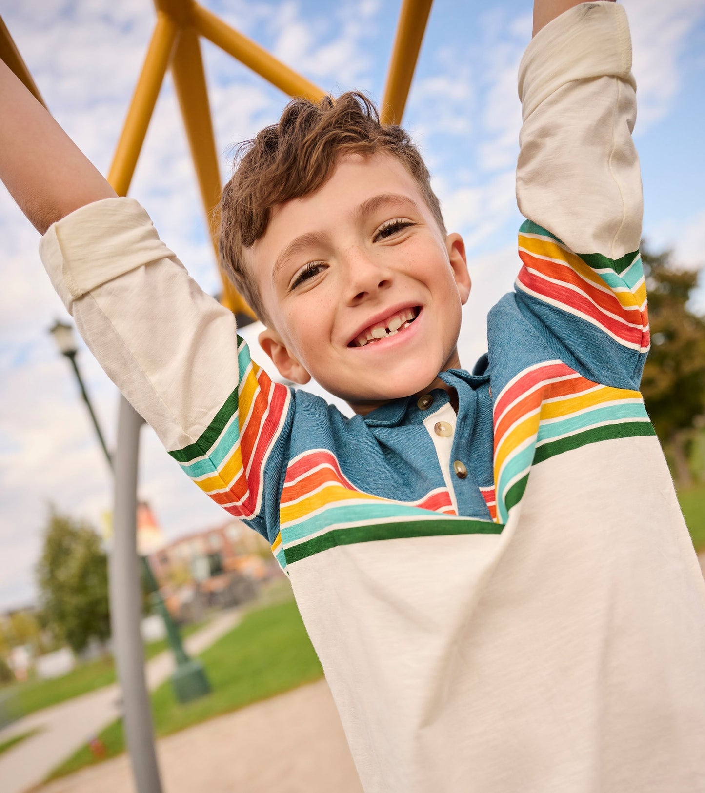 Long sleeve polo featuring retro stripes in blue, red, yellow, and green on a cream background, perfect for casual wear.