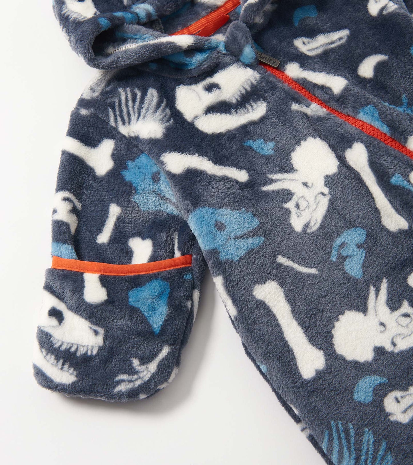 Navy fleece suit featuring dinosaur fossil prints in white and blue, with an orange trim and a hood.