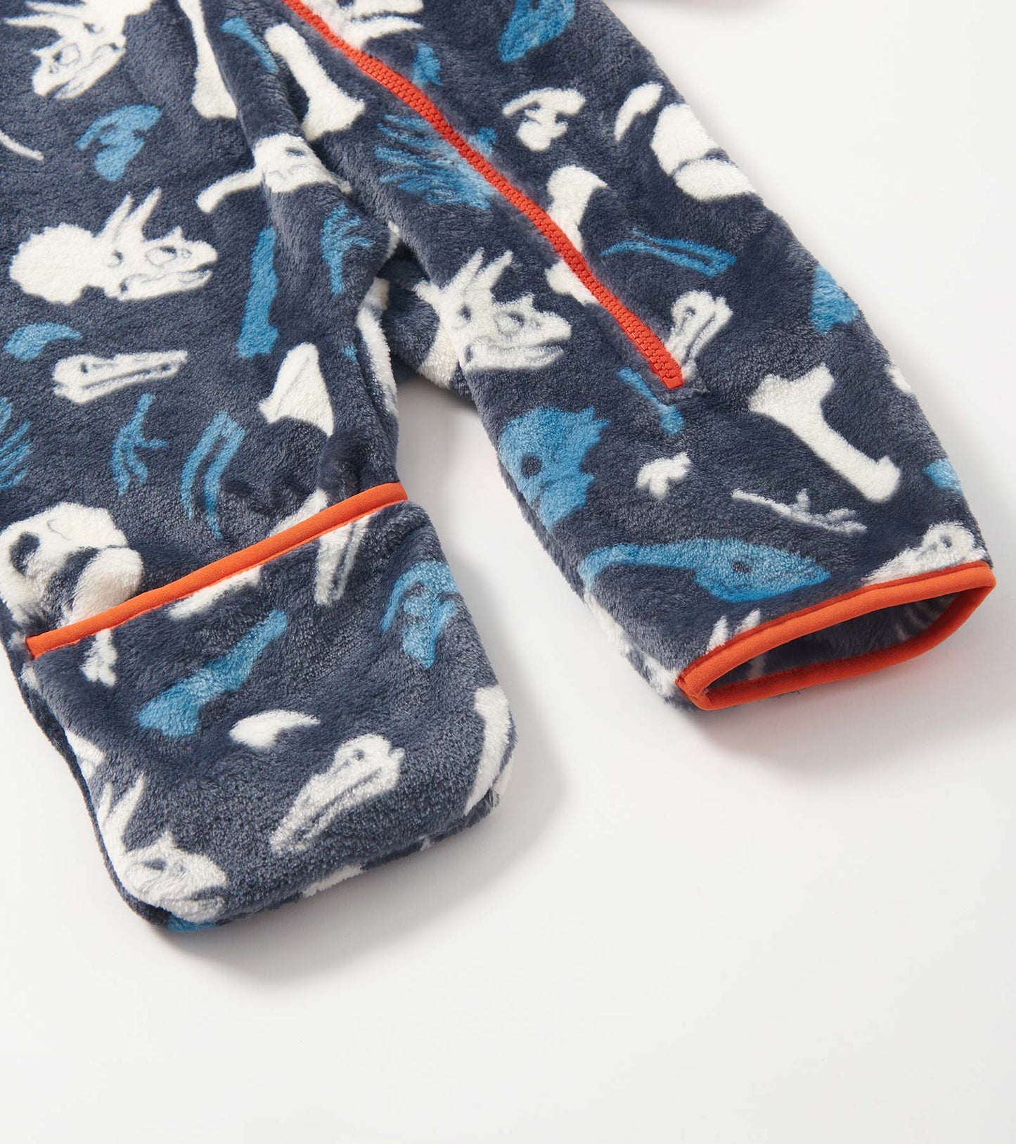 Navy fleece suit featuring white and blue dinosaur fossils, with orange trim on cuffs and zipper. Suitable for baby boys.