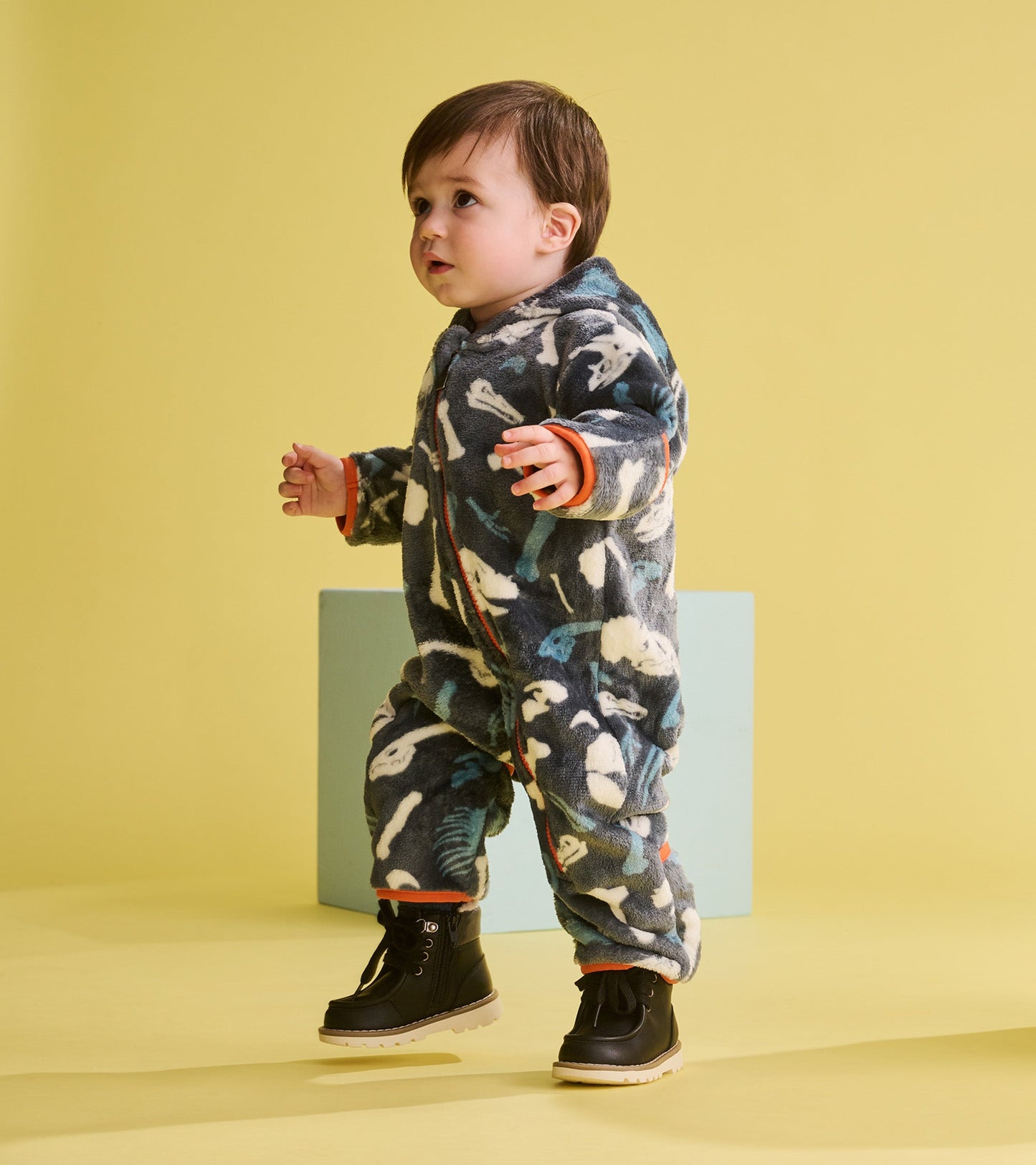 Fleece suit for baby boys featuring a dinosaur fossil pattern in dark blue and white, with orange accents and a cozy fit.