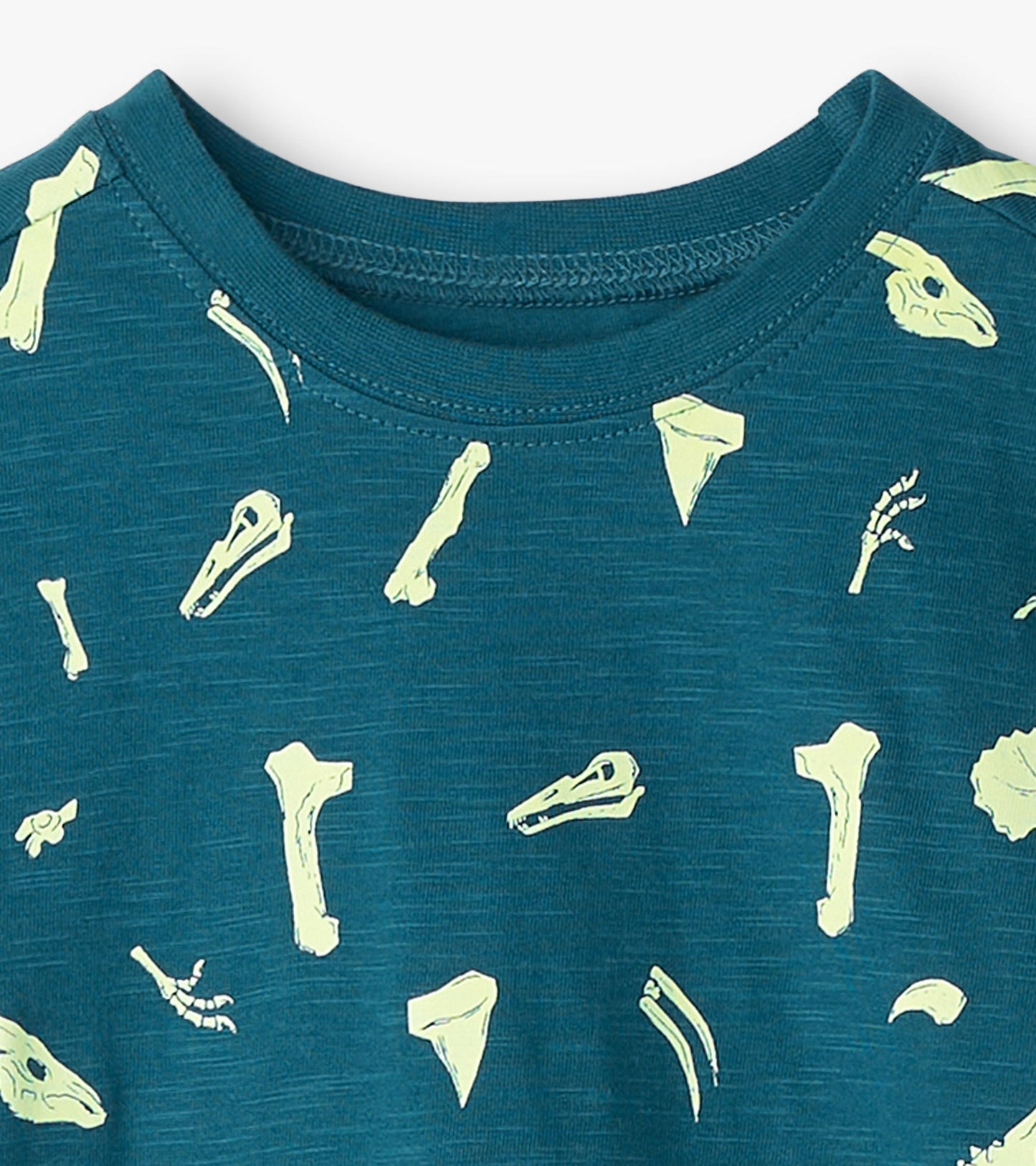 Teal graphic tee featuring glow-in-the-dark dinosaur fossils in various shapes and sizes.