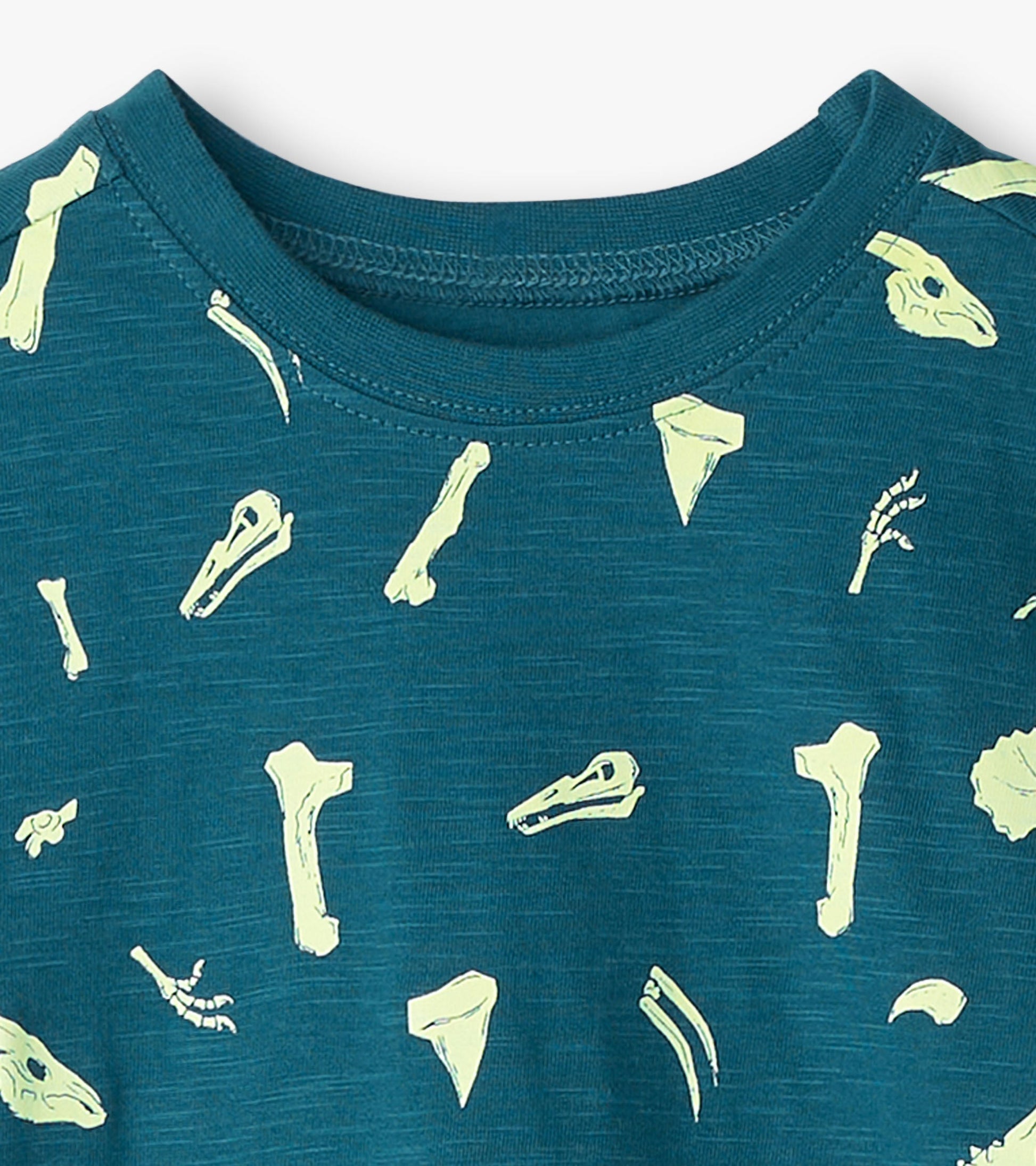 Teal graphic tee featuring glow-in-the-dark dinosaur fossils in various shapes and sizes.