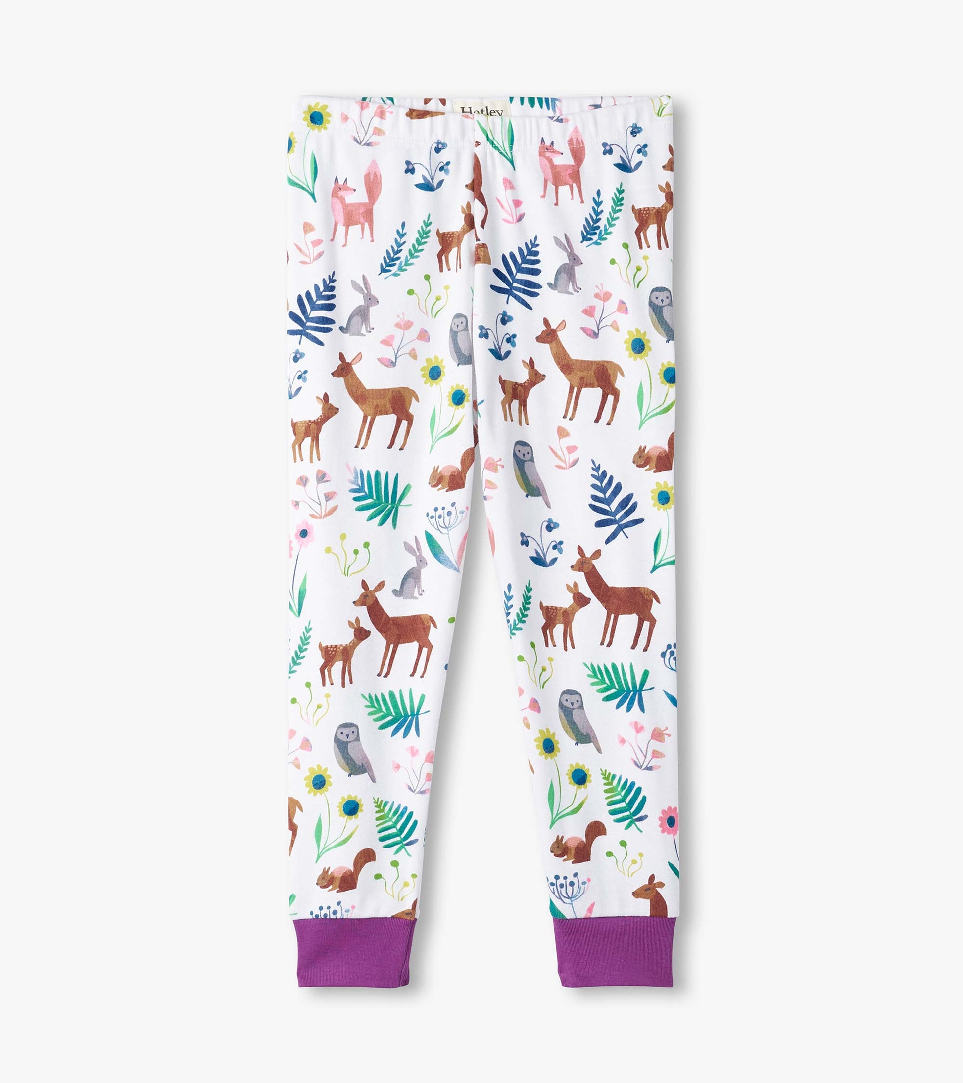 White pajama pants featuring colorful forest creatures and floral patterns, with purple cuffs at the ankles.