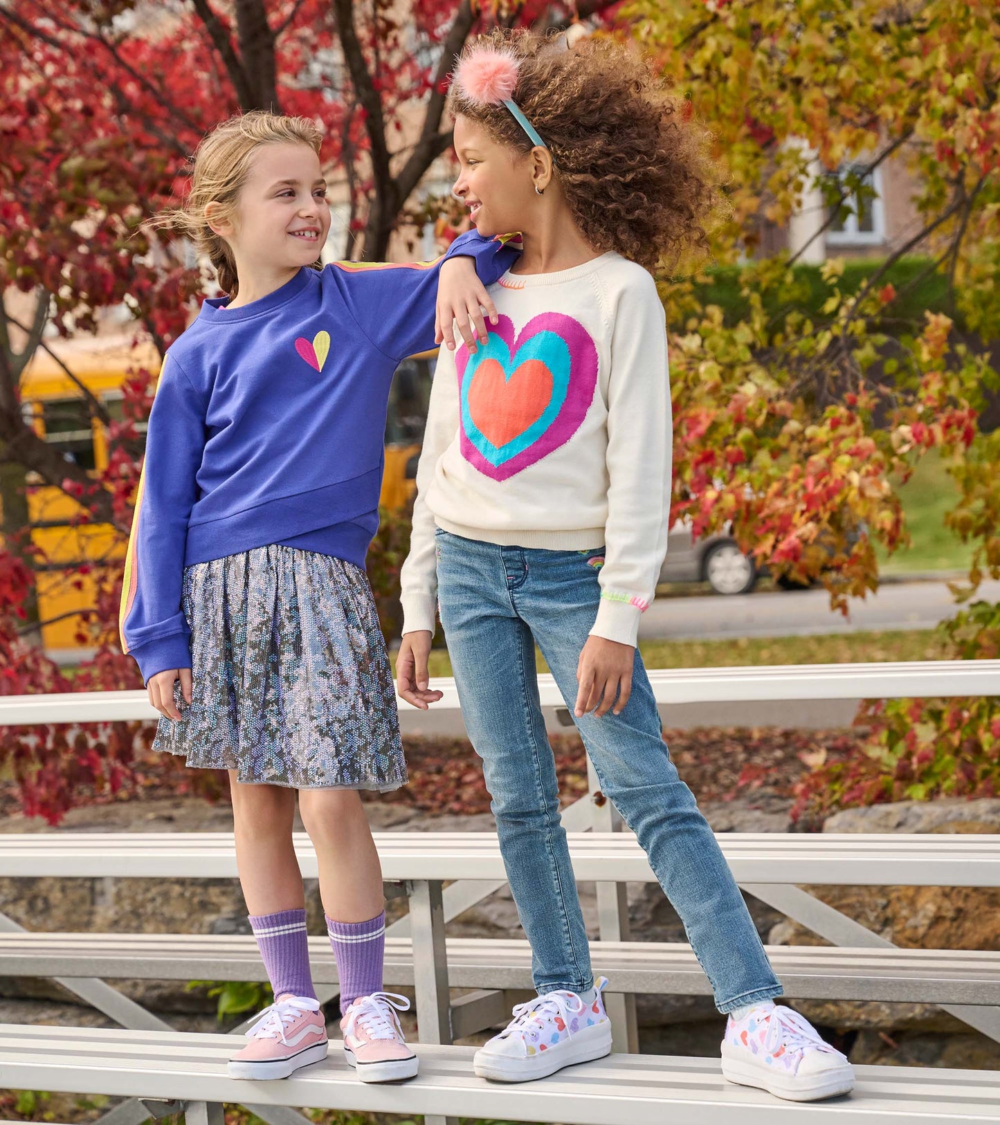 Girls' tulle skirt with shimmering sequins in floral pattern, paired with a colorful heart sweater and casual sneakers.