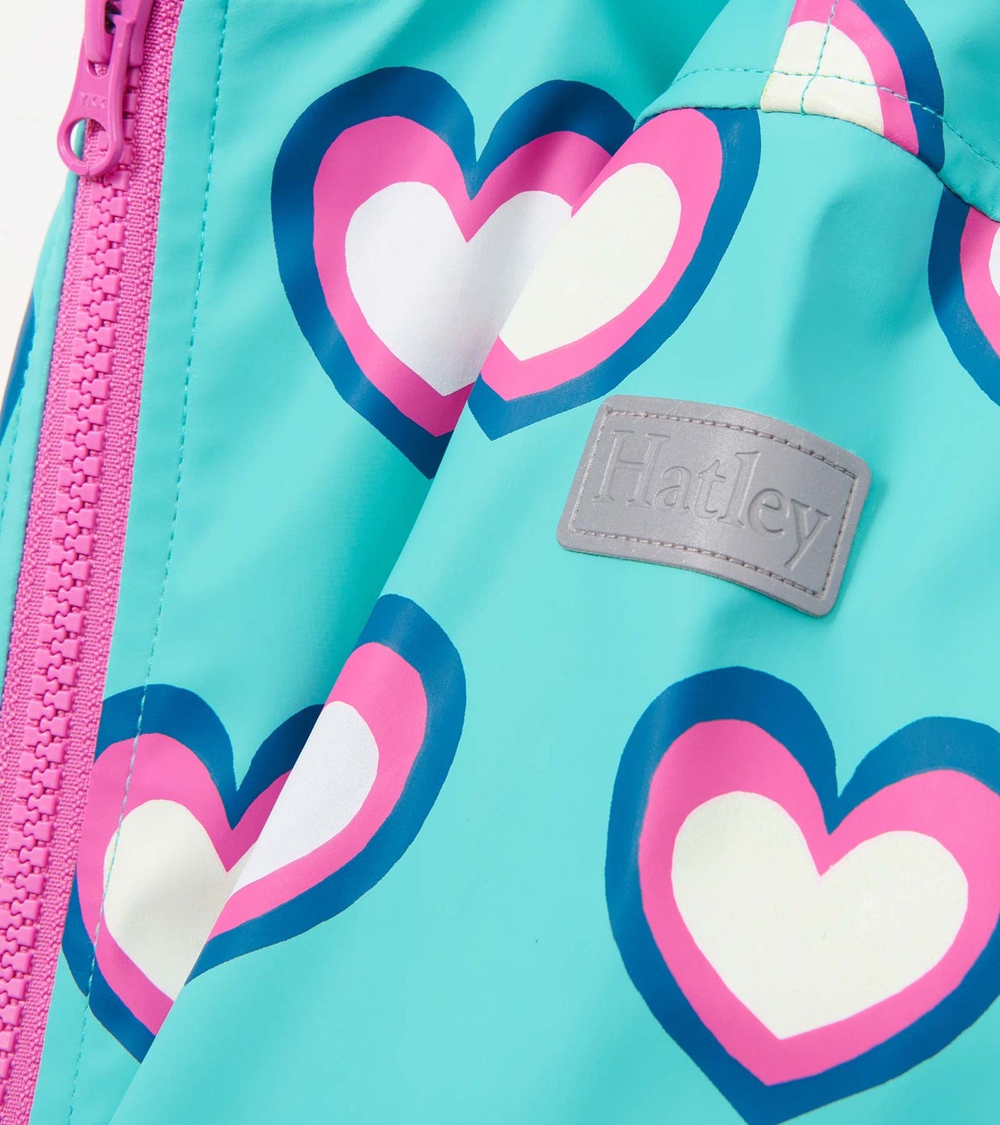 A turquoise zip-up rain jacket featuring colorful heart patterns and a pink zipper.