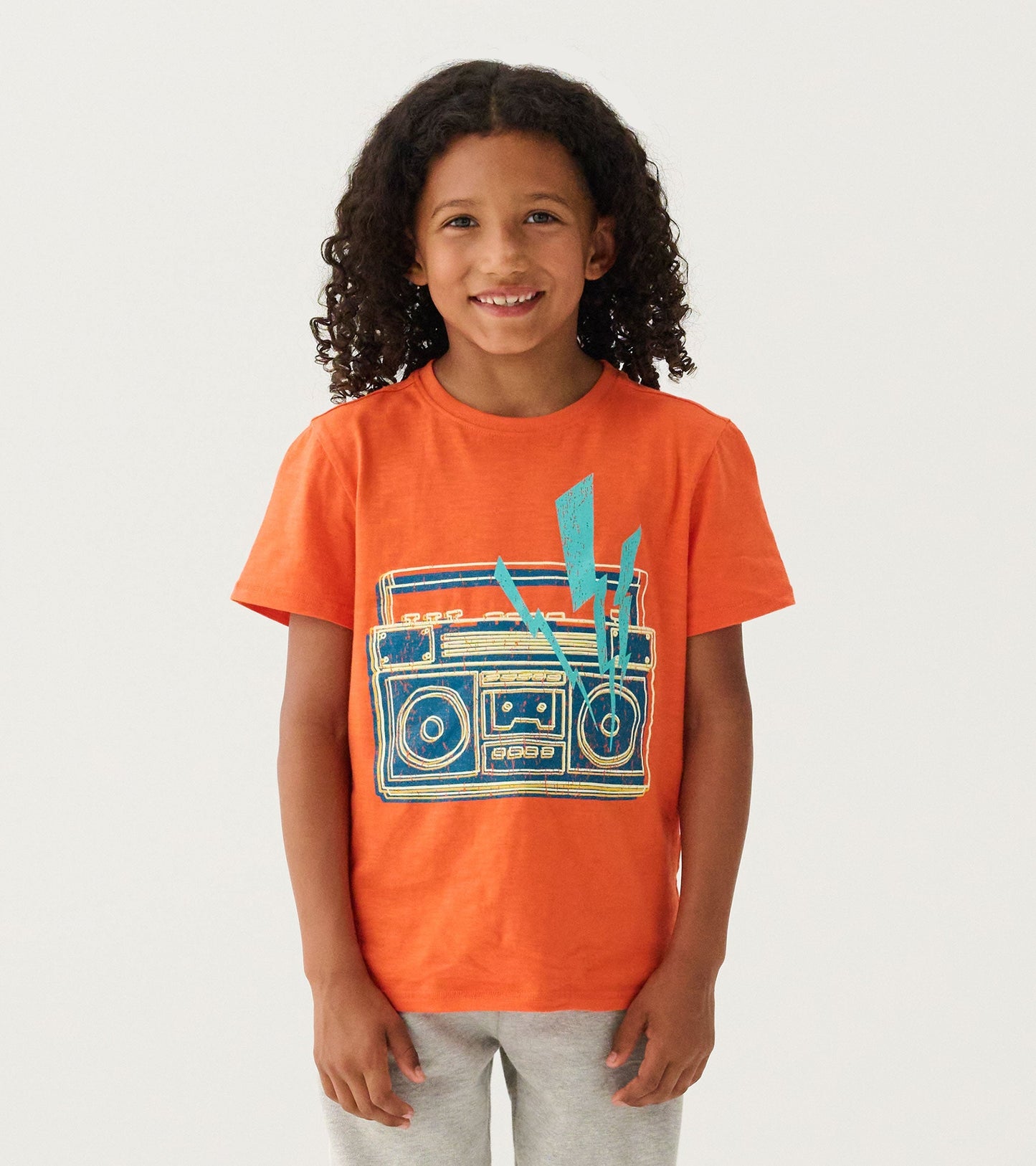 Orange graphic tee featuring a glow-in-the-dark boombox design, suitable for boys.