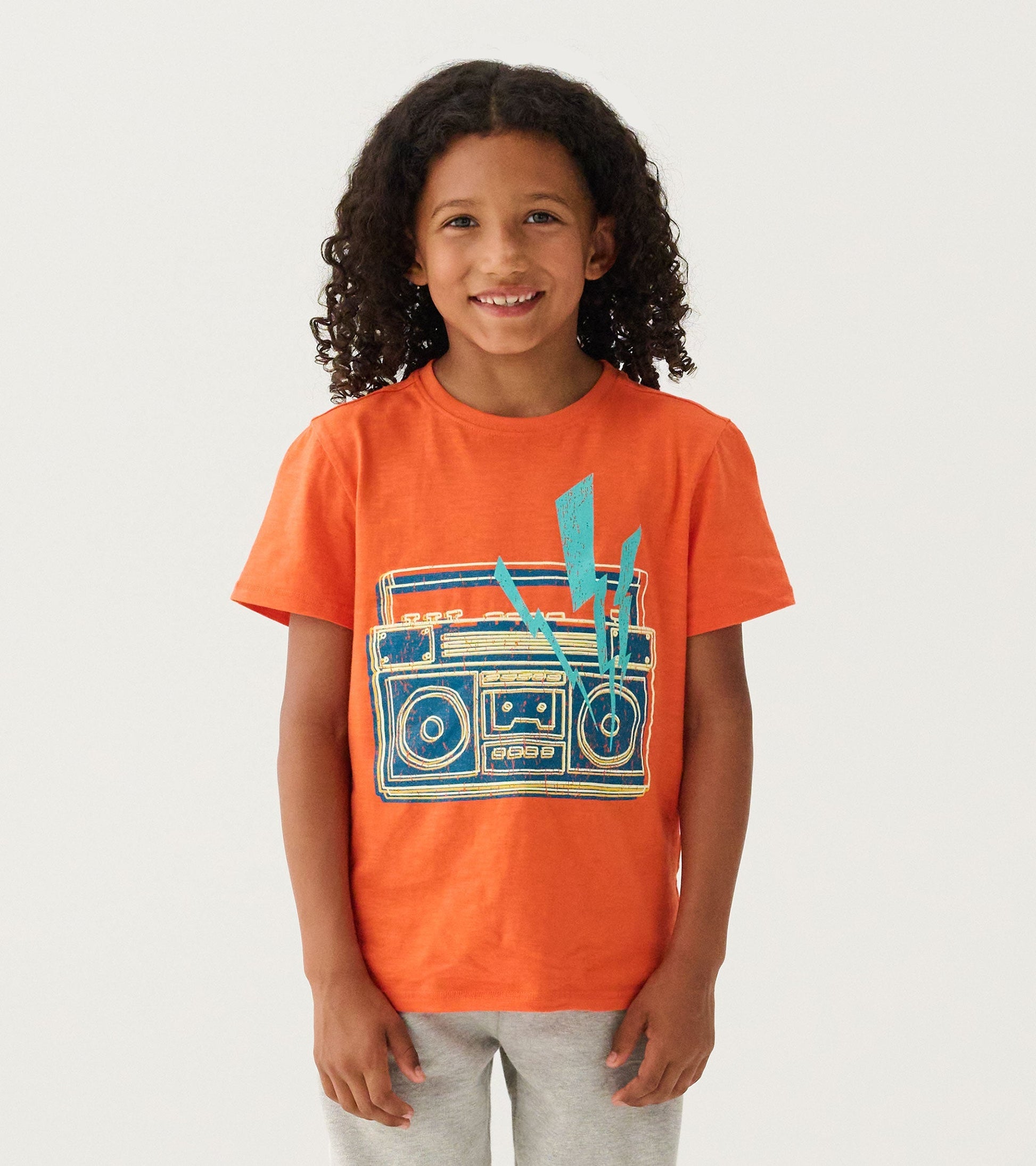 Orange graphic tee featuring a glow-in-the-dark boombox design, suitable for boys.
