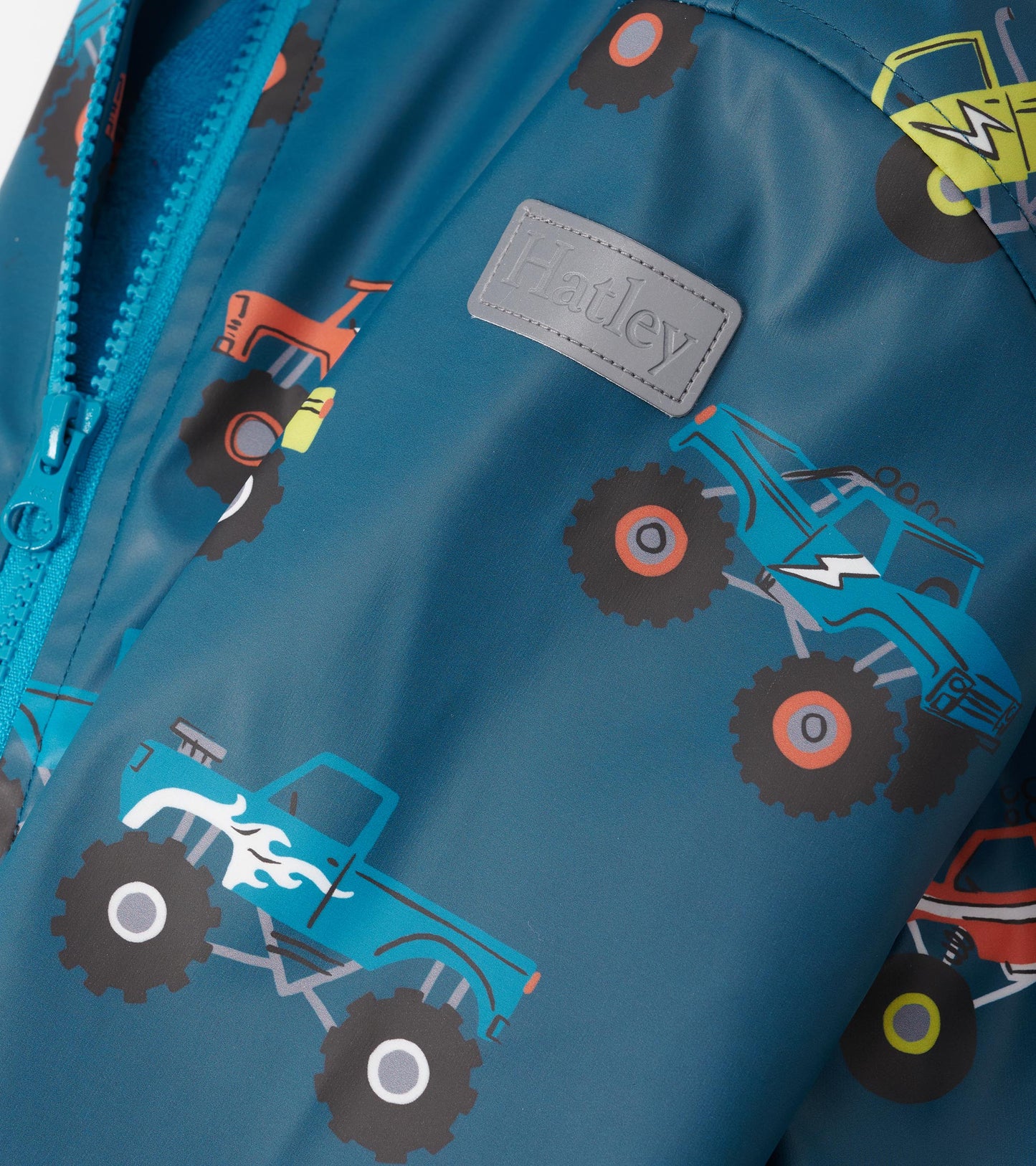 Teal zip-up rain jacket featuring colorful monster truck patterns, perfect for boys.