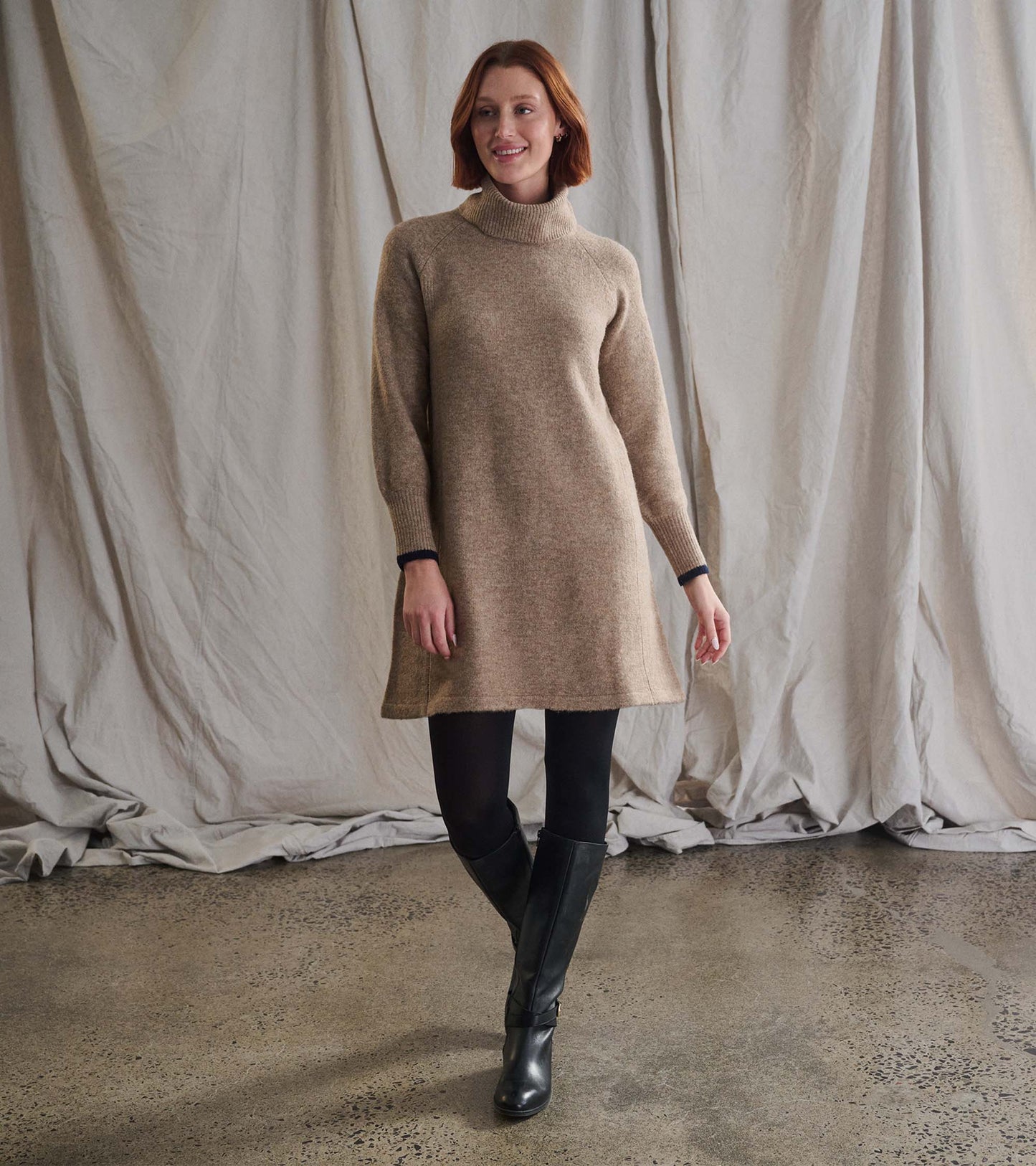 Oatmeal heather sweater dress with a high neckline and long sleeves, styled with black leggings and knee-high boots.