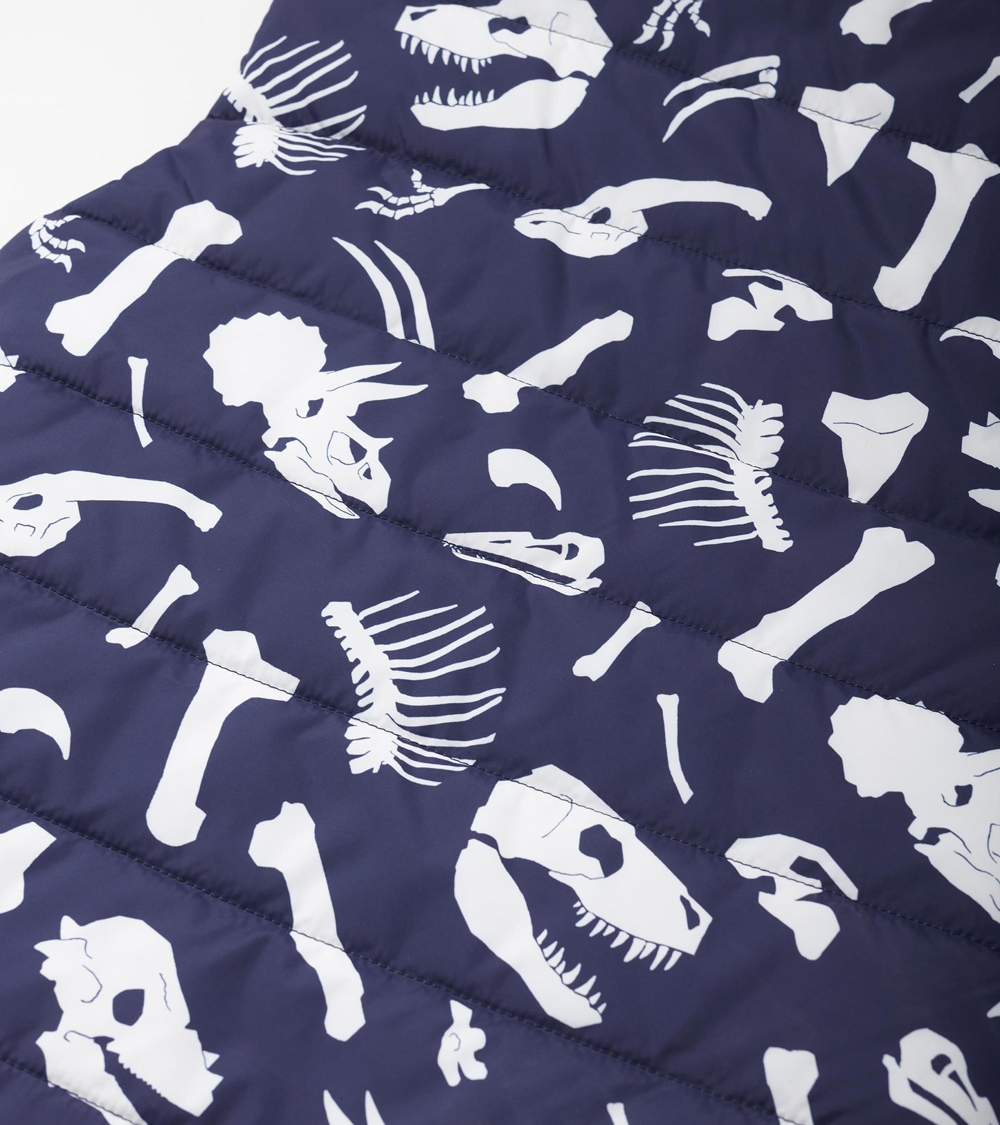 Navy quilted vest featuring white dinosaur fossil prints, ideal for layering in cool weather.