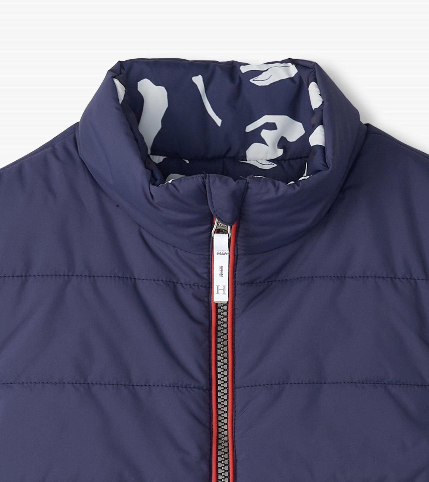 Navy quilted vest with a high collar and red zipper, featuring a white dinosaur fossil pattern on the interior lining.