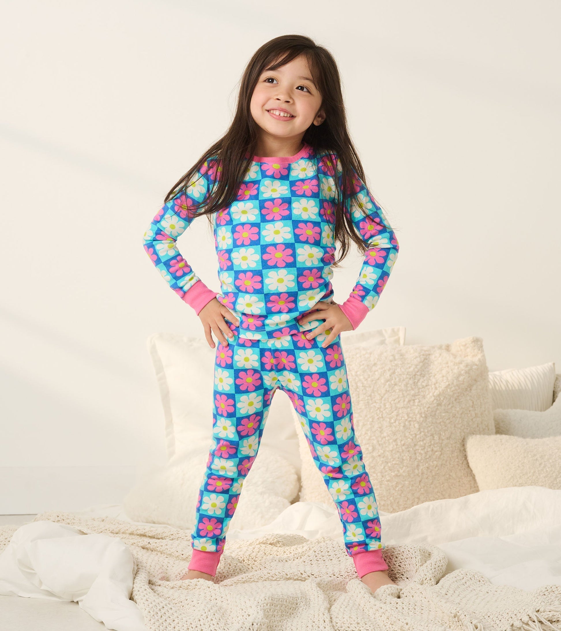 Colorful checkered pajama set featuring daisies, made of organic cotton, with pink cuffs and a playful design.