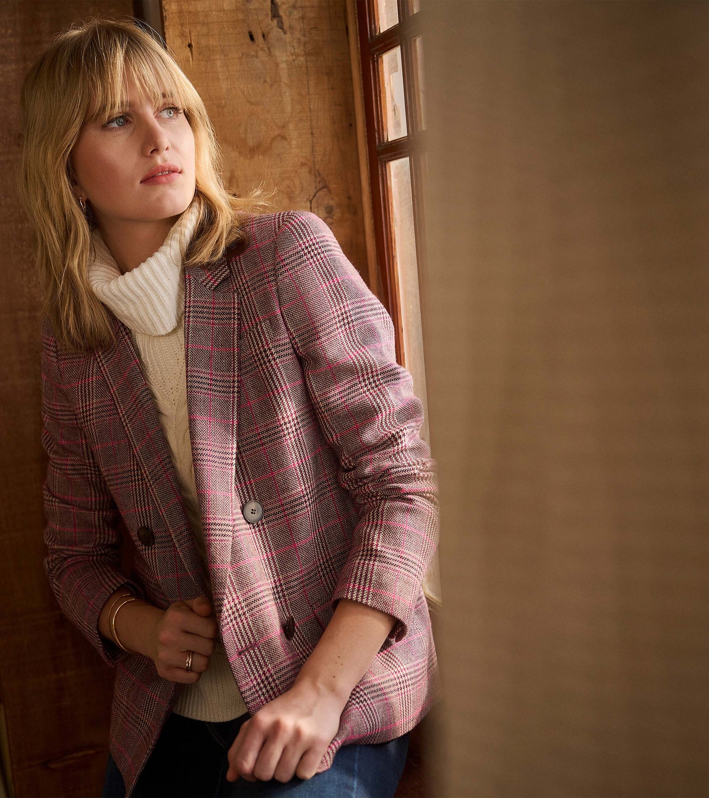 Taupe check semi-fitted blazer with double-breasted buttons, styled over a cream sweater, worn casually.