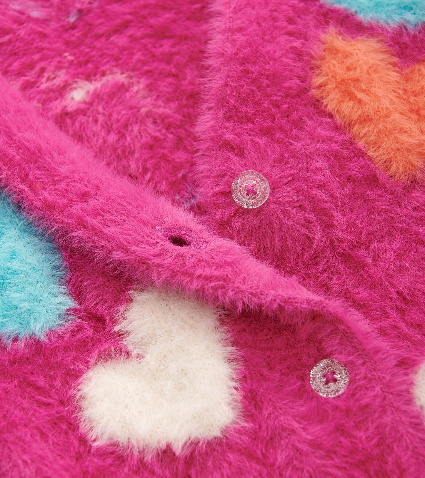 Fuzzy pink cardigan featuring colorful heart patterns and clear buttons, ideal for layering in cooler weather.