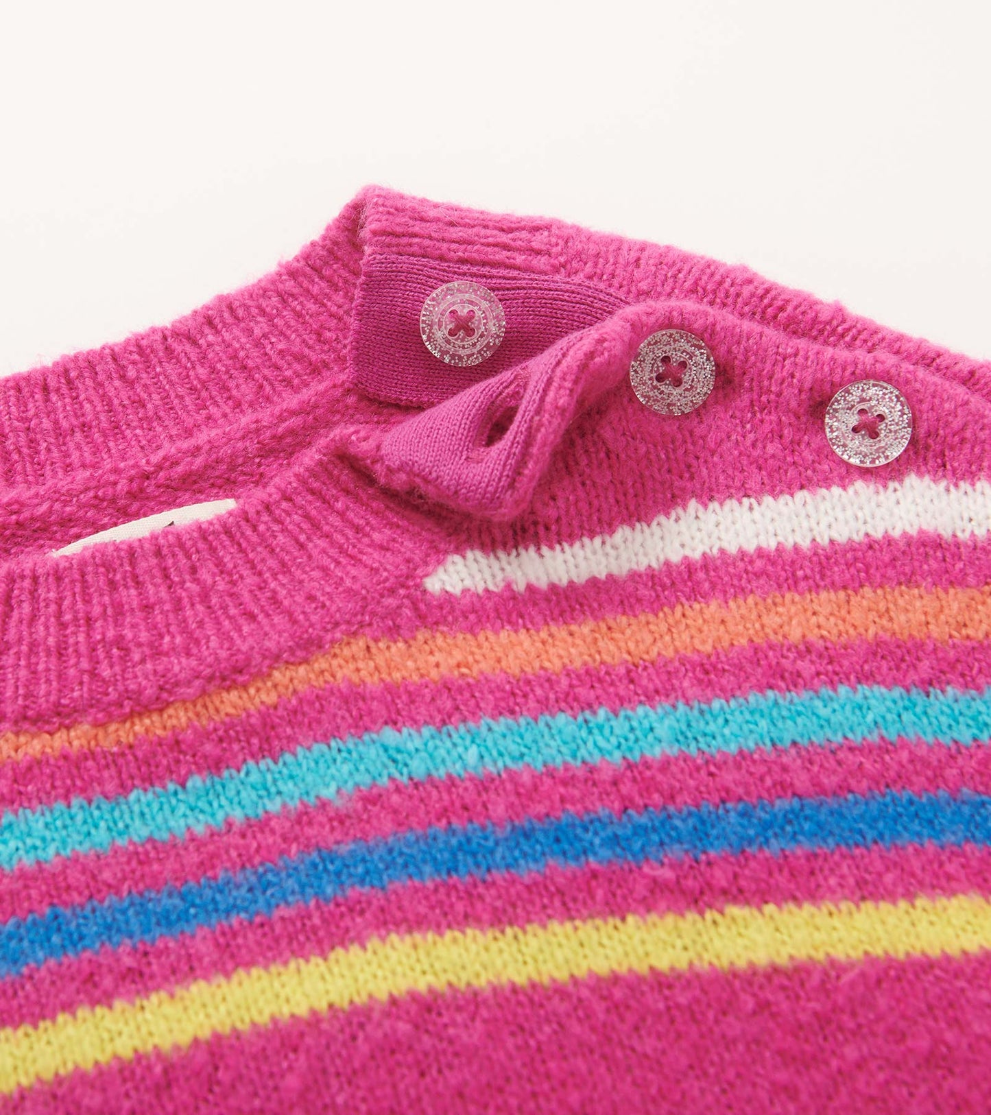 Pink sweater tunic featuring colorful rainbow stripes and decorative buttons at the neckline.