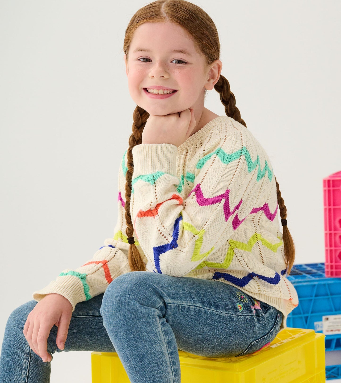 Cream sweater with colorful zigzag pattern, perfect for casual wear, paired with blue jeans.