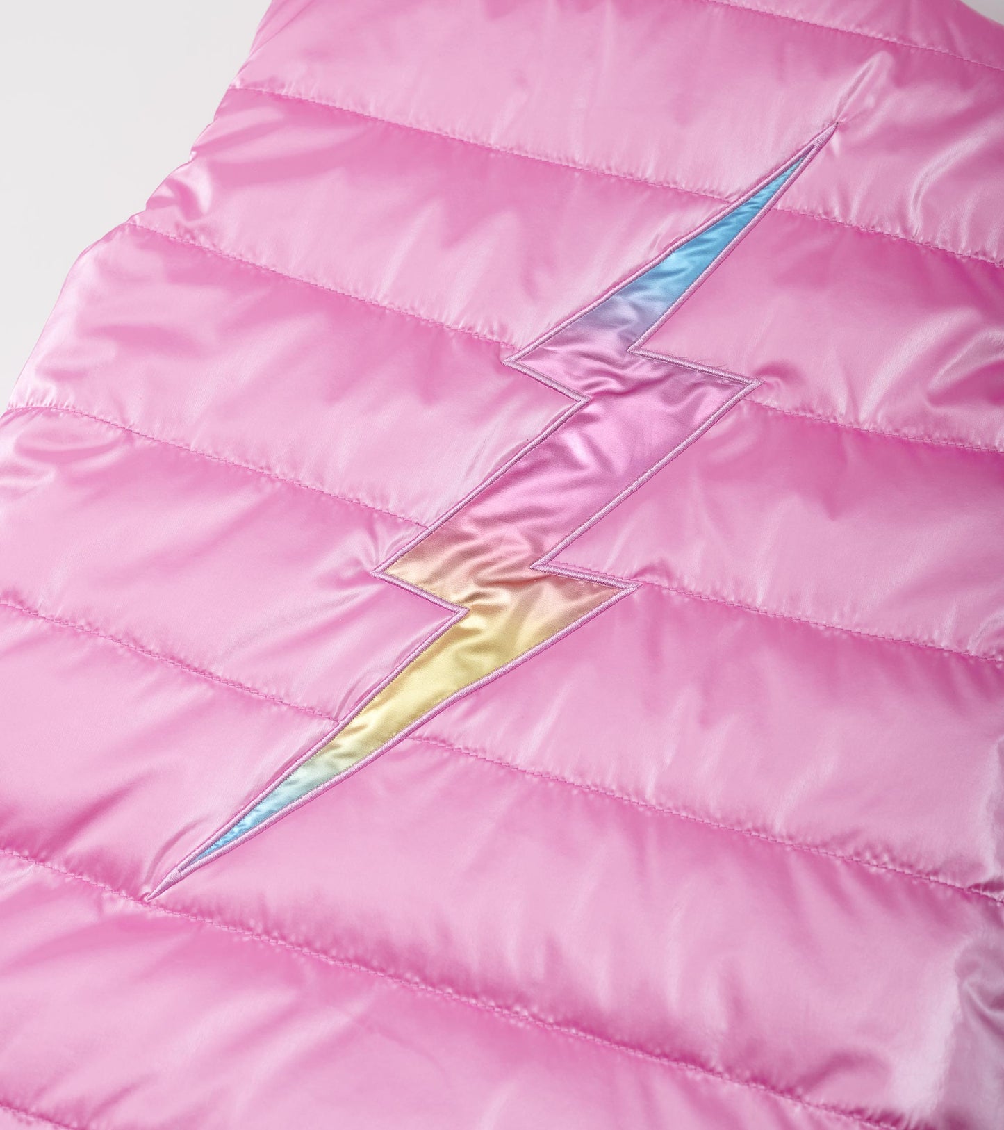 Reversible pink quilted vest featuring a colorful lightning bolt design on the front.