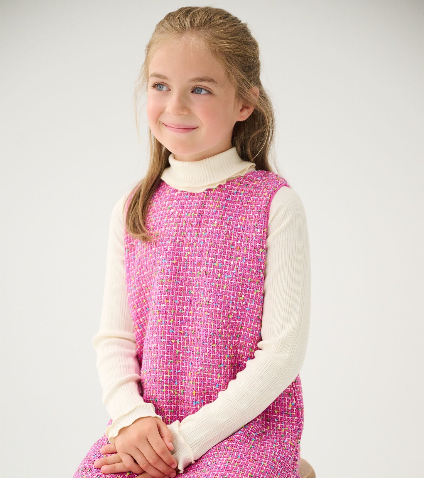 Girls' sleeveless dress in rose violet tweed with a textured pattern, paired with a white long-sleeve top.