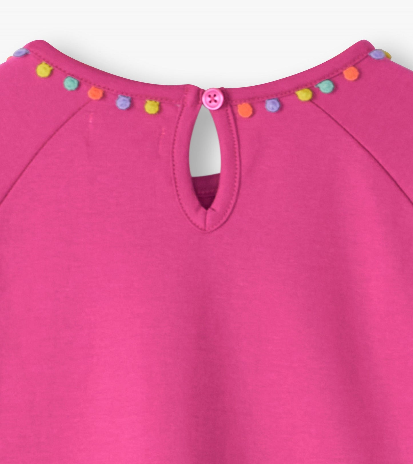 Pink gathered dress featuring a keyhole back and colorful pom-pom trim along the neckline.