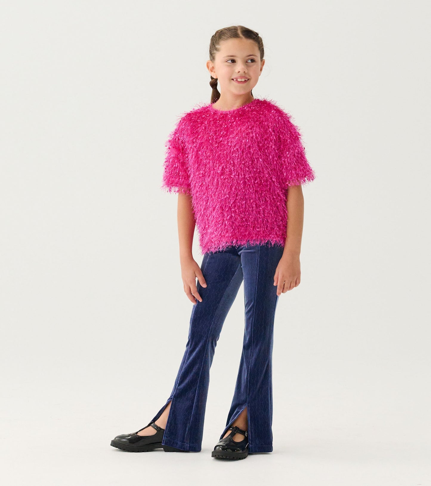 Fluffy pink knit sweater with short sleeves, paired with dark blue flared pants and black shoes, worn by a smiling girl.