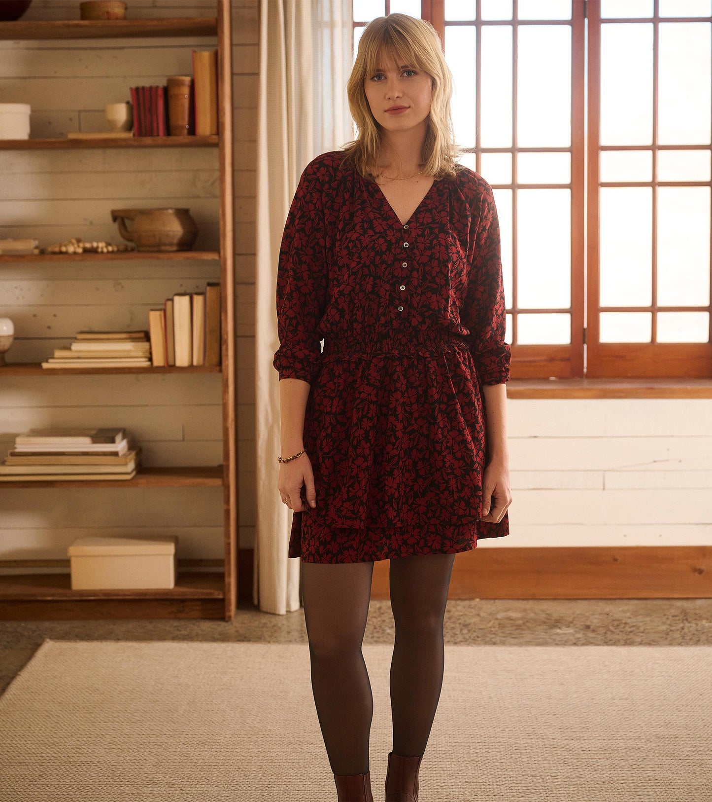 Red floral smocked waist dress with long sleeves and a V-neck, styled with tights and ankle boots.
