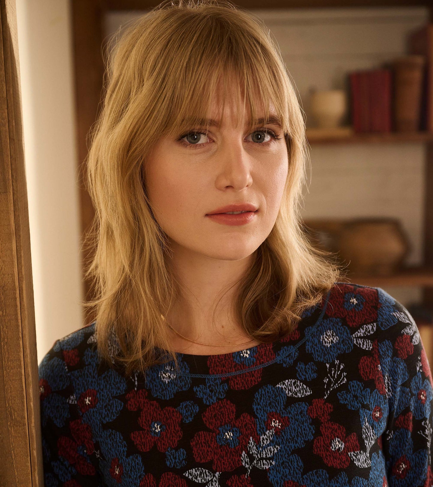 Woman wearing a black long-sleeve dress with red, blue, and white floral print, front view