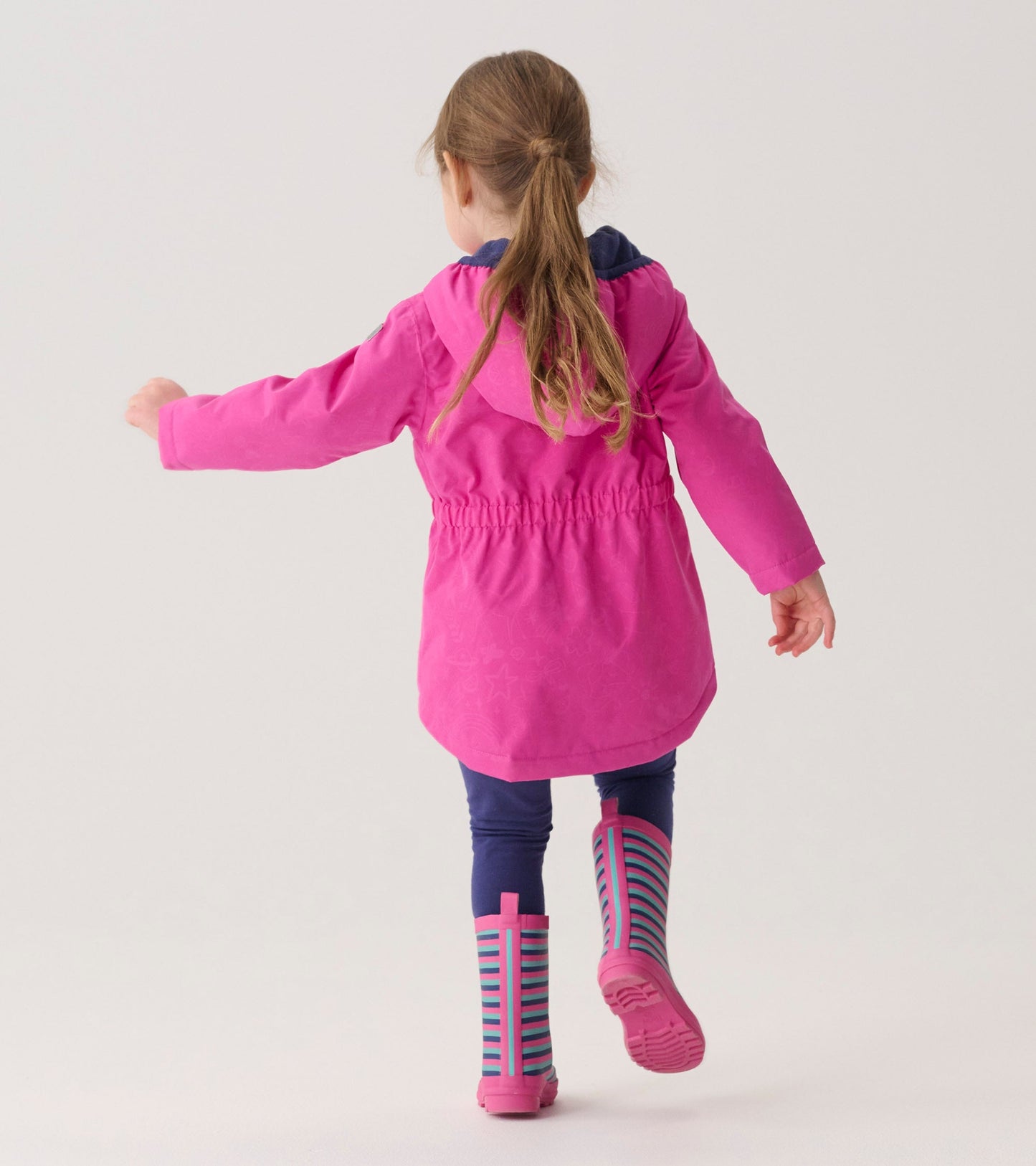 Lightweight pink zip-up rain jacket with a hood, featuring an elastic waist, worn by a girl with striped rain boots.