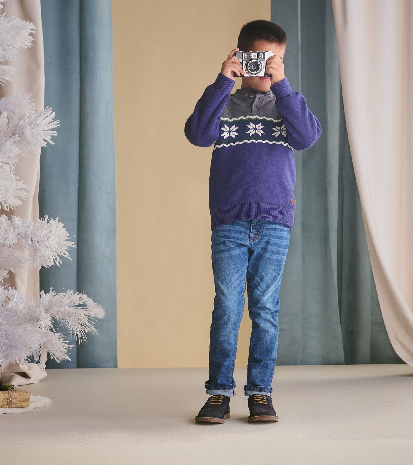 Boys' winter knit mockneck sweater in purple with gray and white snowflake pattern, worn with blue jeans.