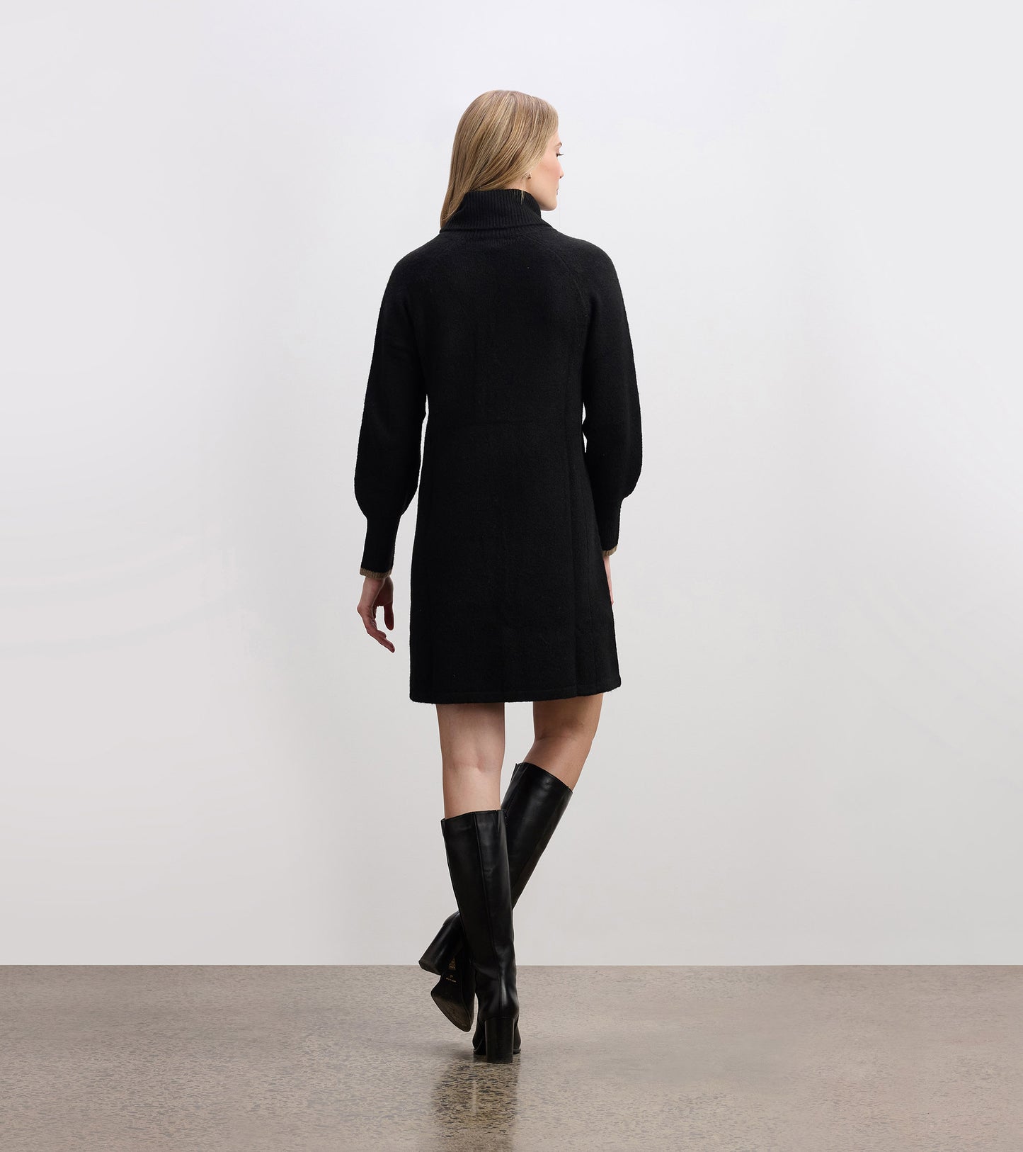 Black swing sweater dress with a high collar and long sleeves, styled with knee-high black boots.