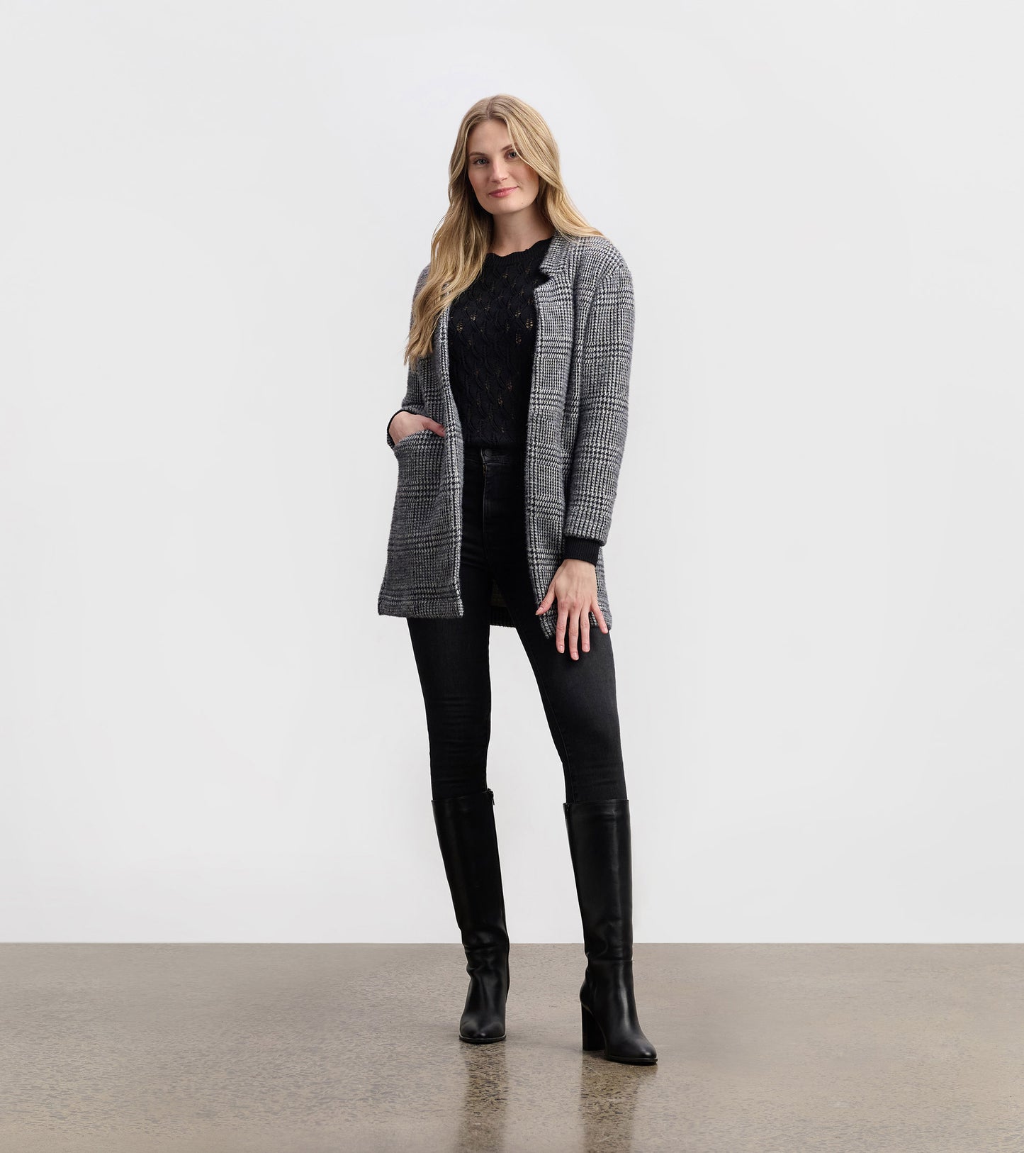 Cozy black check open blazer with pockets, styled over a black top and paired with black jeans and knee-high boots.