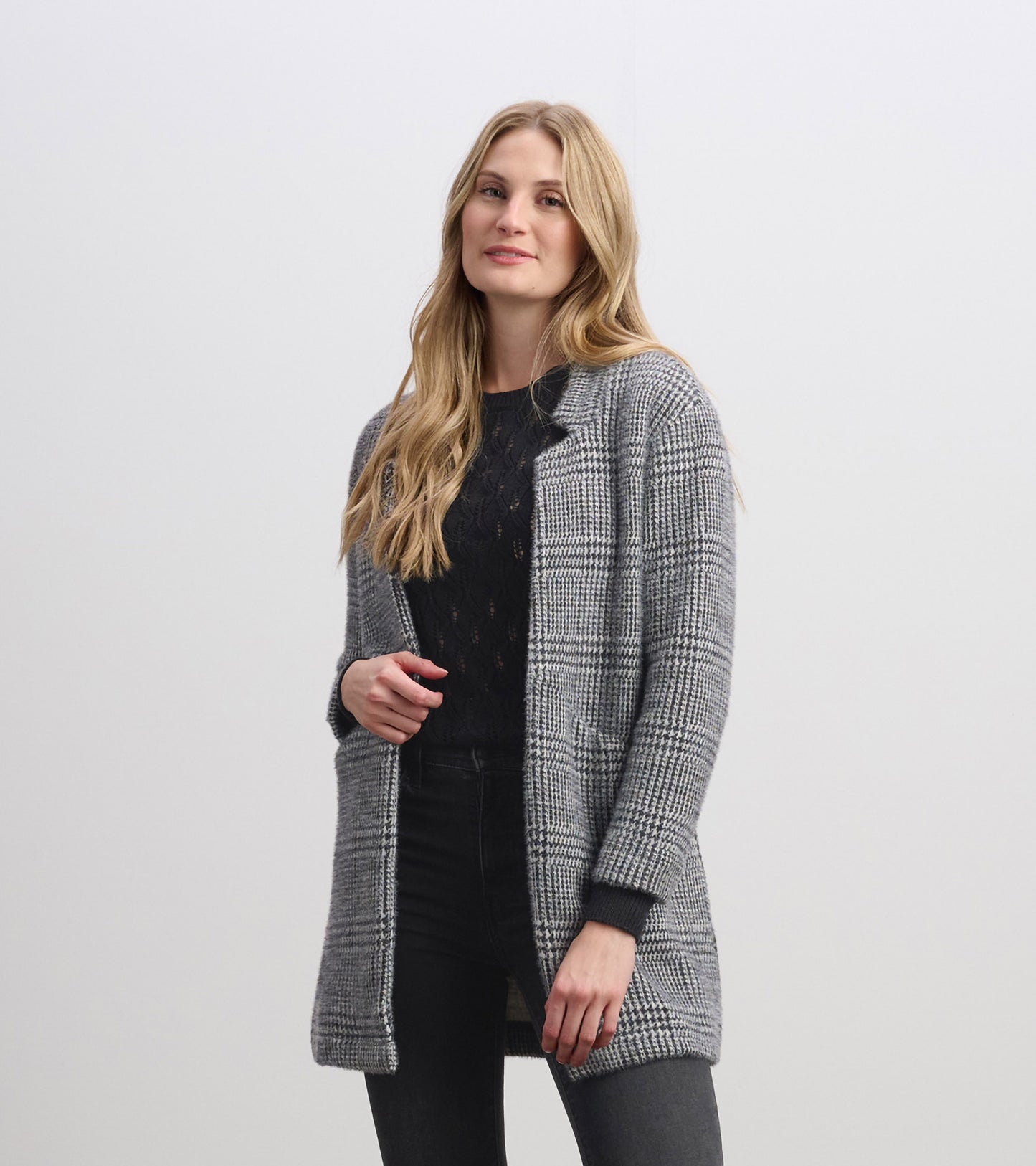 Cozy black check open blazer with long sleeves, featuring a relaxed fit and front pockets, styled over a black top.