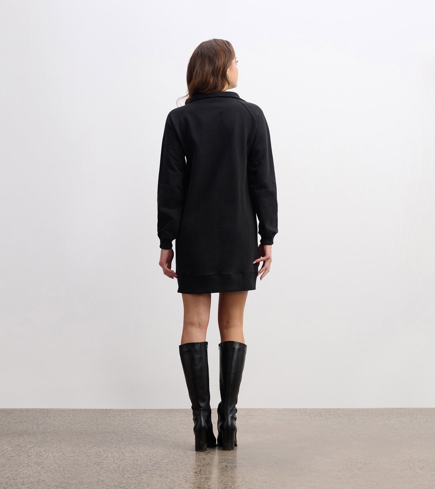 Black notch neck dress with long sleeves, knee-length, and a relaxed fit, styled with knee-high black boots.