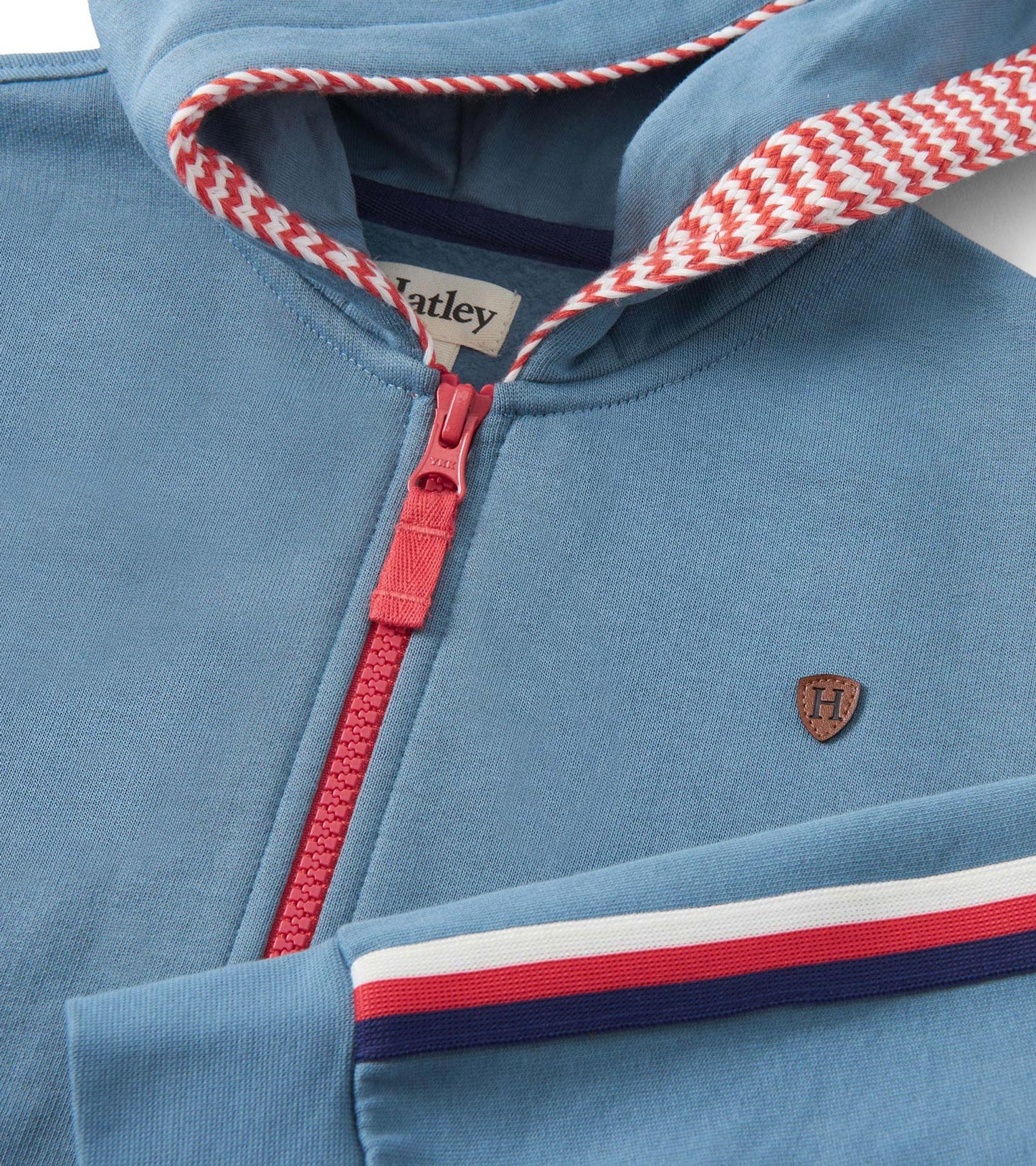 Blue zip-up hoodie featuring a red zipper, striped hood lining, and a small emblem on the chest.