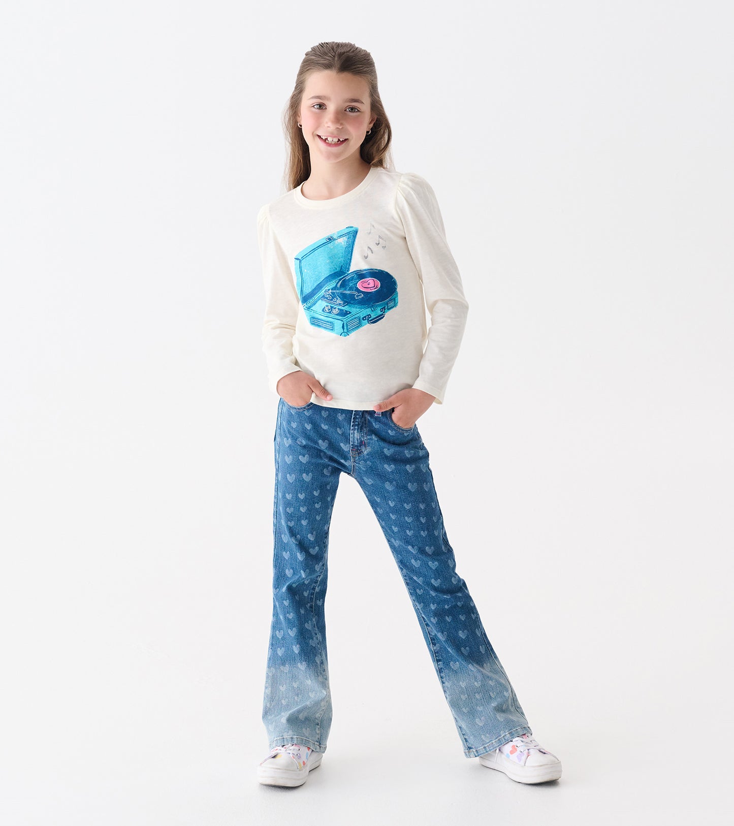 Cream long-sleeve tee with puff sleeves featuring a blue graphic of a record player. Paired with heart-patterned jeans.