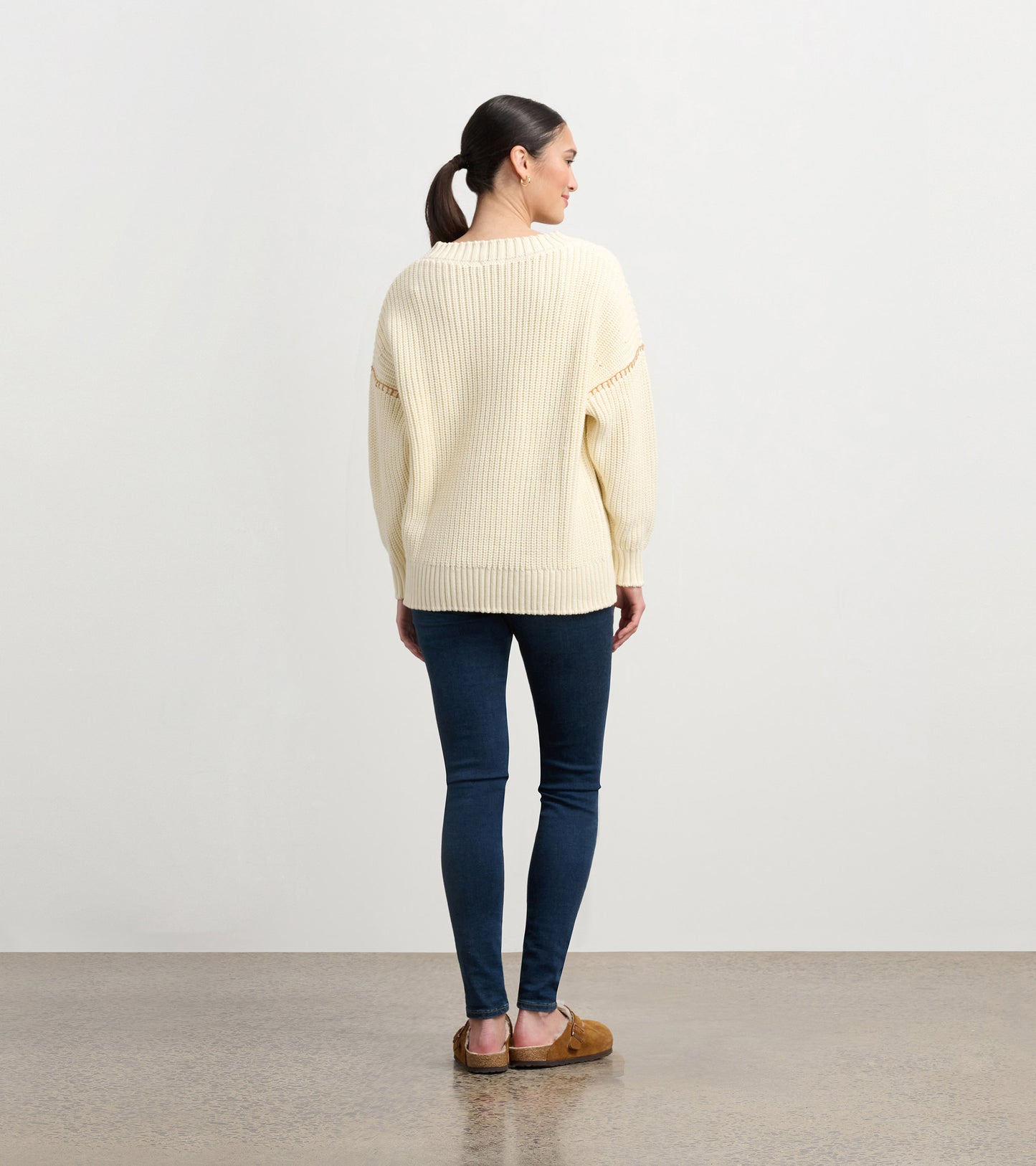 Cream V-neck slouchy sweater with ribbed texture, paired with dark skinny jeans, viewed from the back.