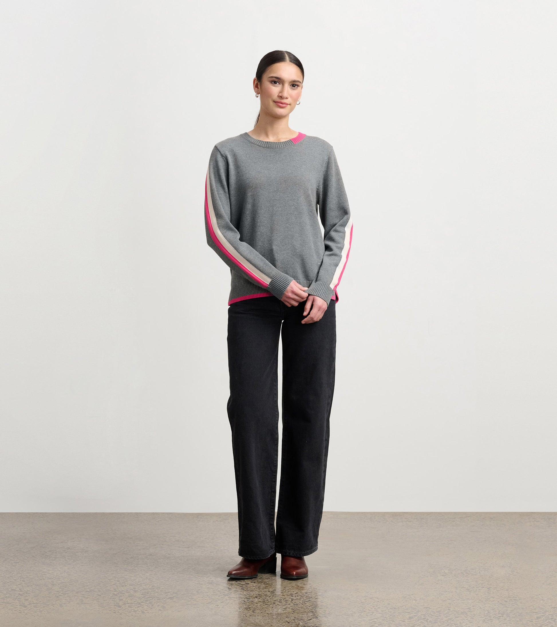 Charcoal sweater with pink contrast trim, featuring a crew neckline and long sleeves, styled with black pants.