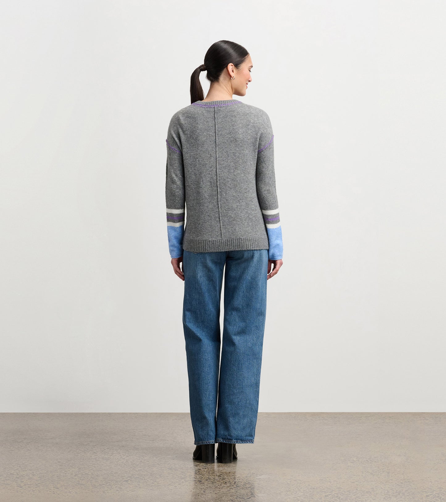 Charcoal melange sweater with colorful striped sleeves, featuring a relaxed fit and ribbed hem, viewed from the back.