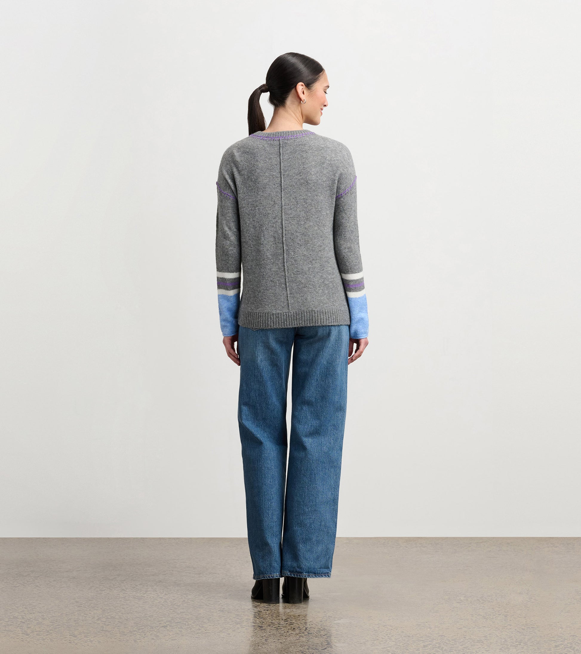 Charcoal melange sweater with colorful striped sleeves, featuring a relaxed fit and ribbed hem, viewed from the back.